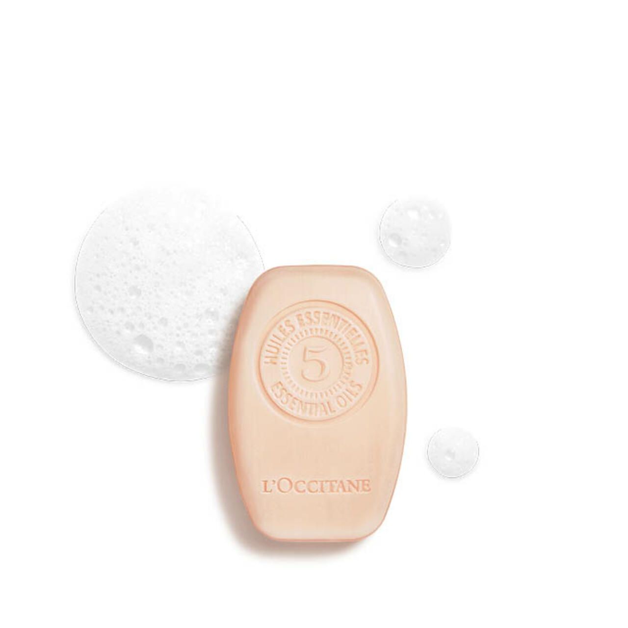 Ovales Shampoo-Stück mit Prägung. Aufschrift: Huiles Essentielles, 5, L'Occitane. Schaumblasen.