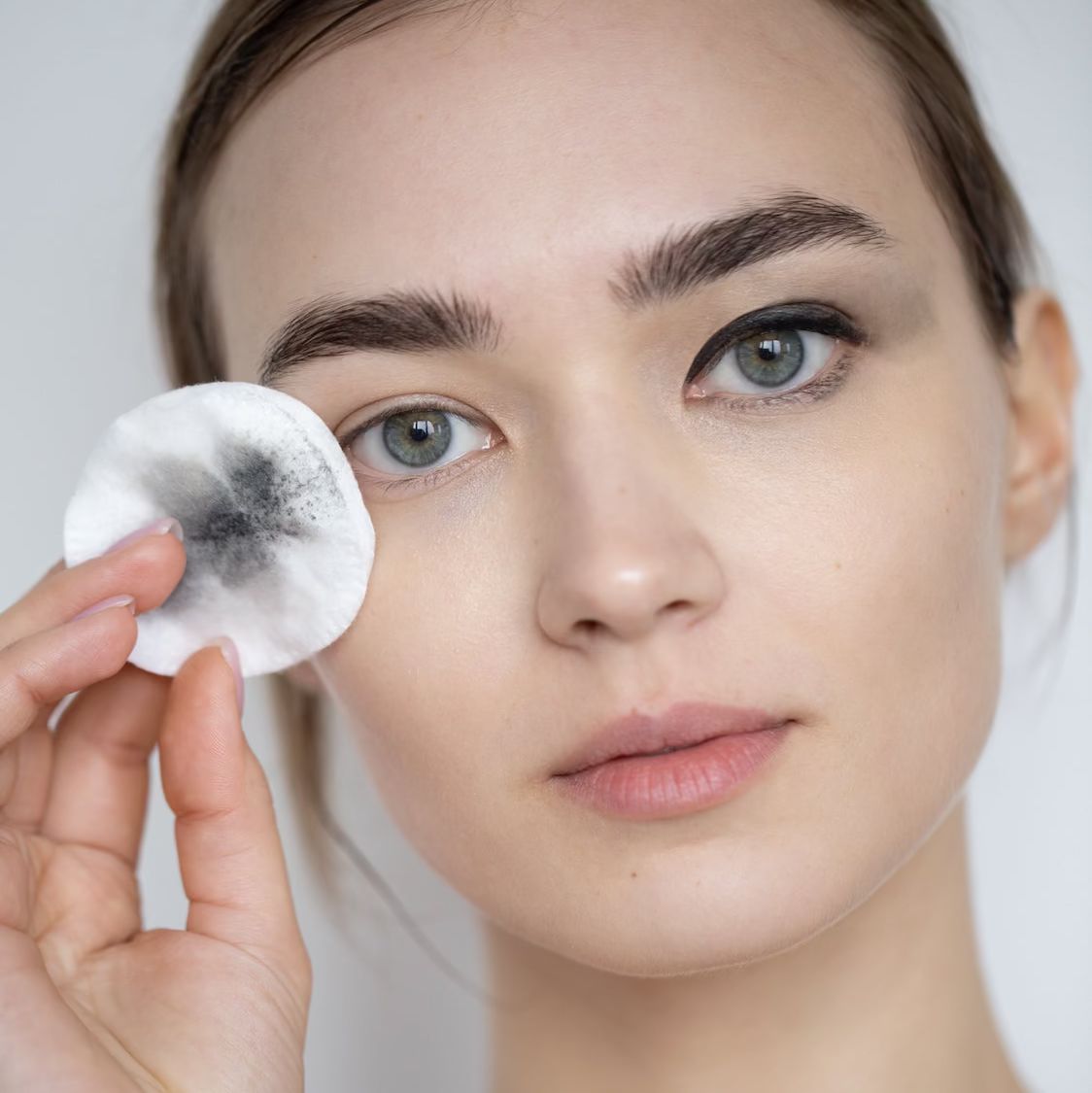 Frau mit Wattepad, das Make-up vom Auge entfernt.