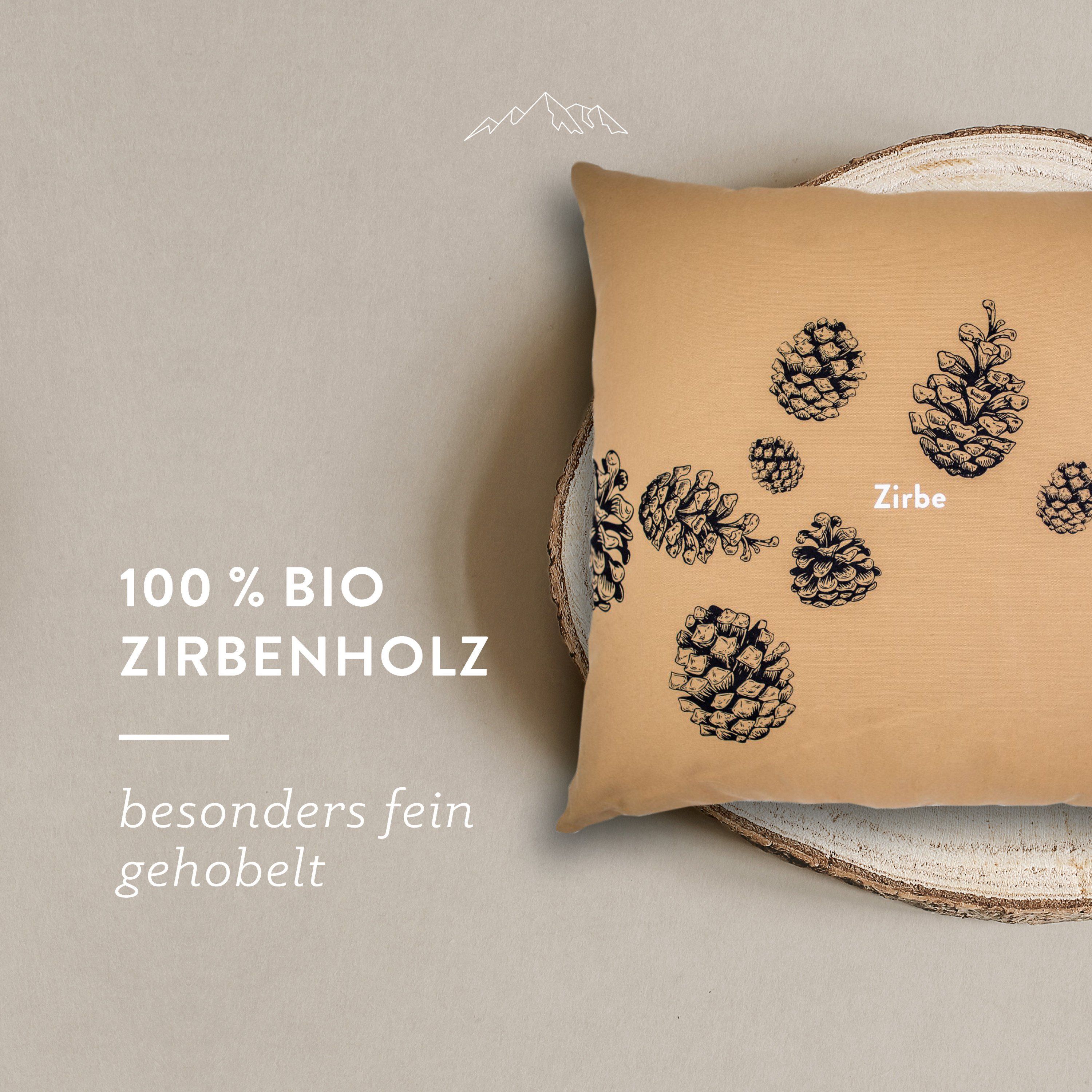 Beiges Kissen mit Kiefernzapfen-Motiv auf Holzscheibe. Text: 100% Bio Zirbenholz, besonders fein gehobelt.