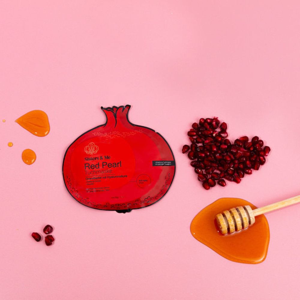 Rote Gesichtsmaske, Granatapfelkerne und Honig auf rosa Untergrund. Produkt von Sisters & Me.
