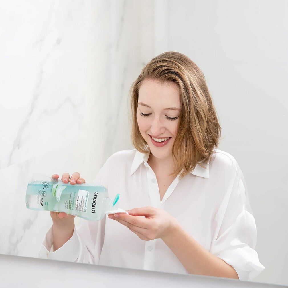 Frau gießt Babaria Micellar Bifasica auf Wattepad. Badezimmerhintergrund. Produkt und Anwendung.