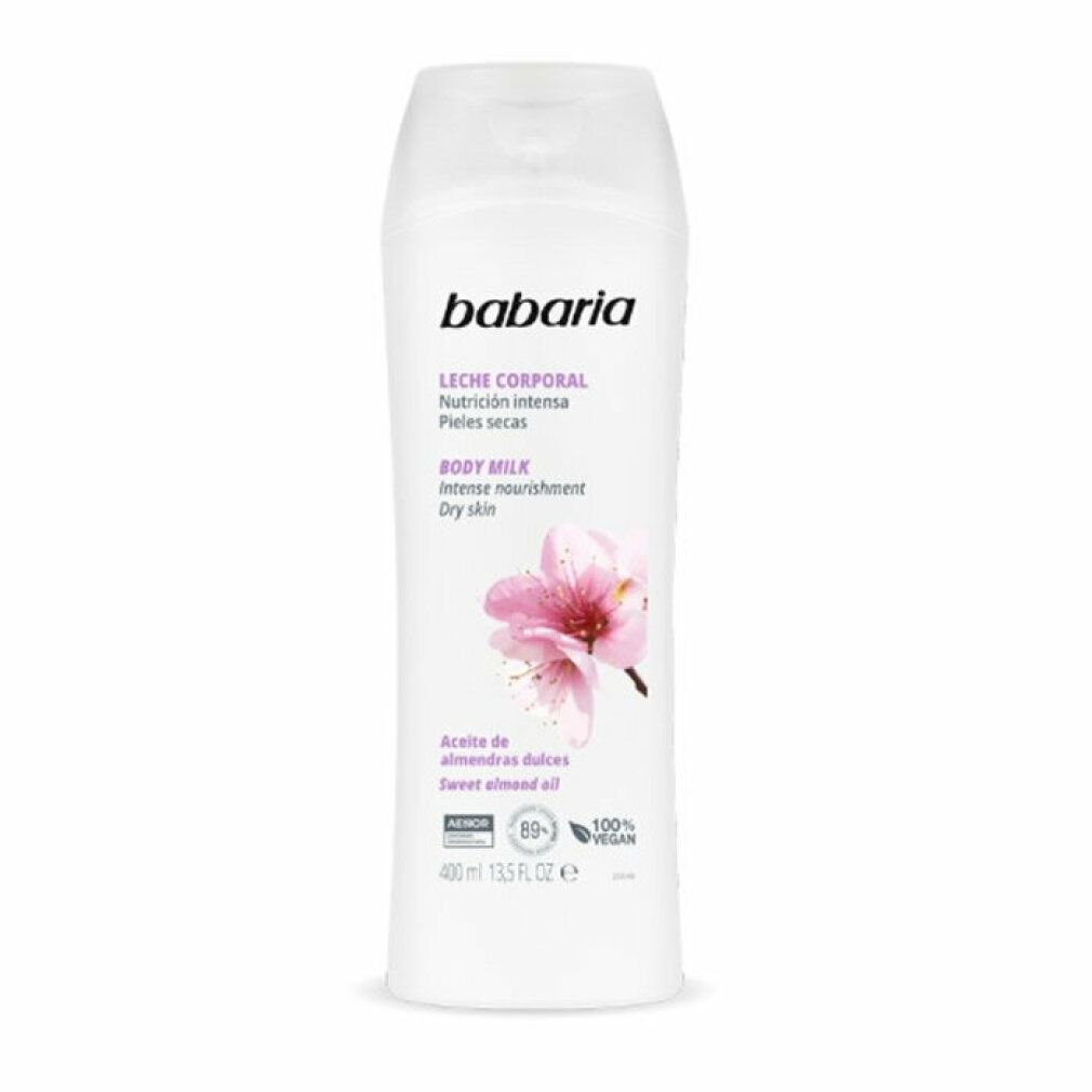 Weiße Flasche Babaria Body Milk. Text: Leche Corporal, Nutrición intensa, Pieles secas, Body Milk, Intense nourishment, Dry skin. Mandelblüten-Illustration.