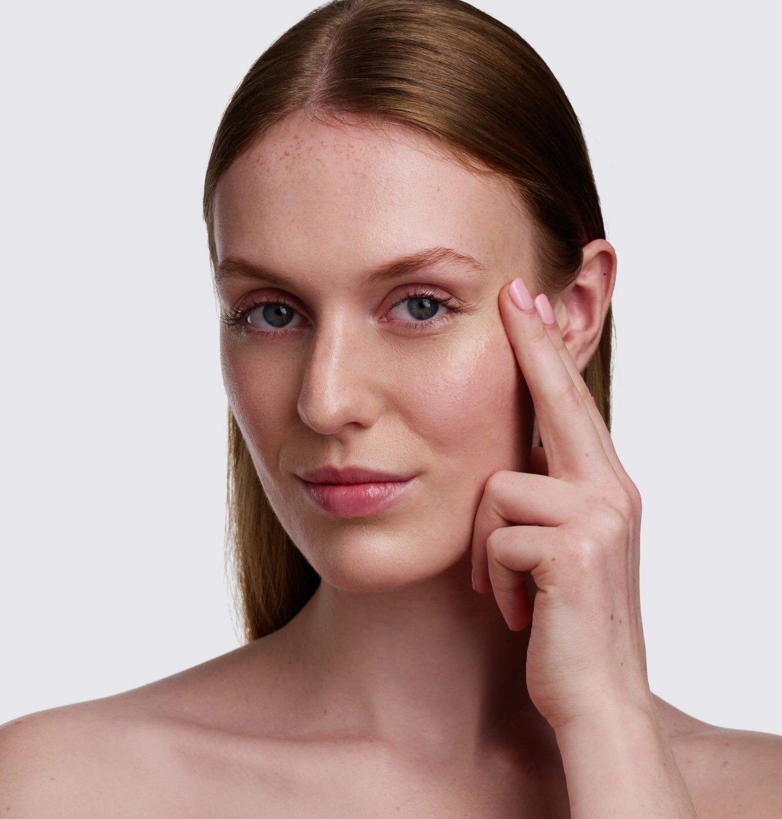 Frau berührt Gesicht. Helle Haut, Blick zur Kamera. Finger berühren die Haut unter dem Auge.