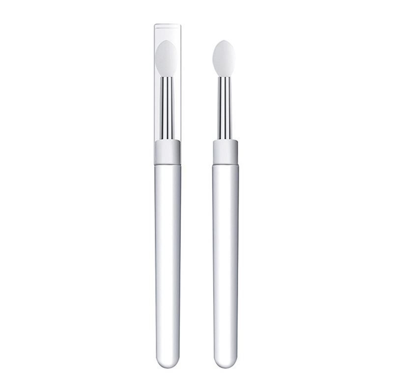 Zwei weiße Lippenbürsten. Eine in einer transparenten Hülle. Beide haben einen weißen Applikator und einen silbernen Stiel.