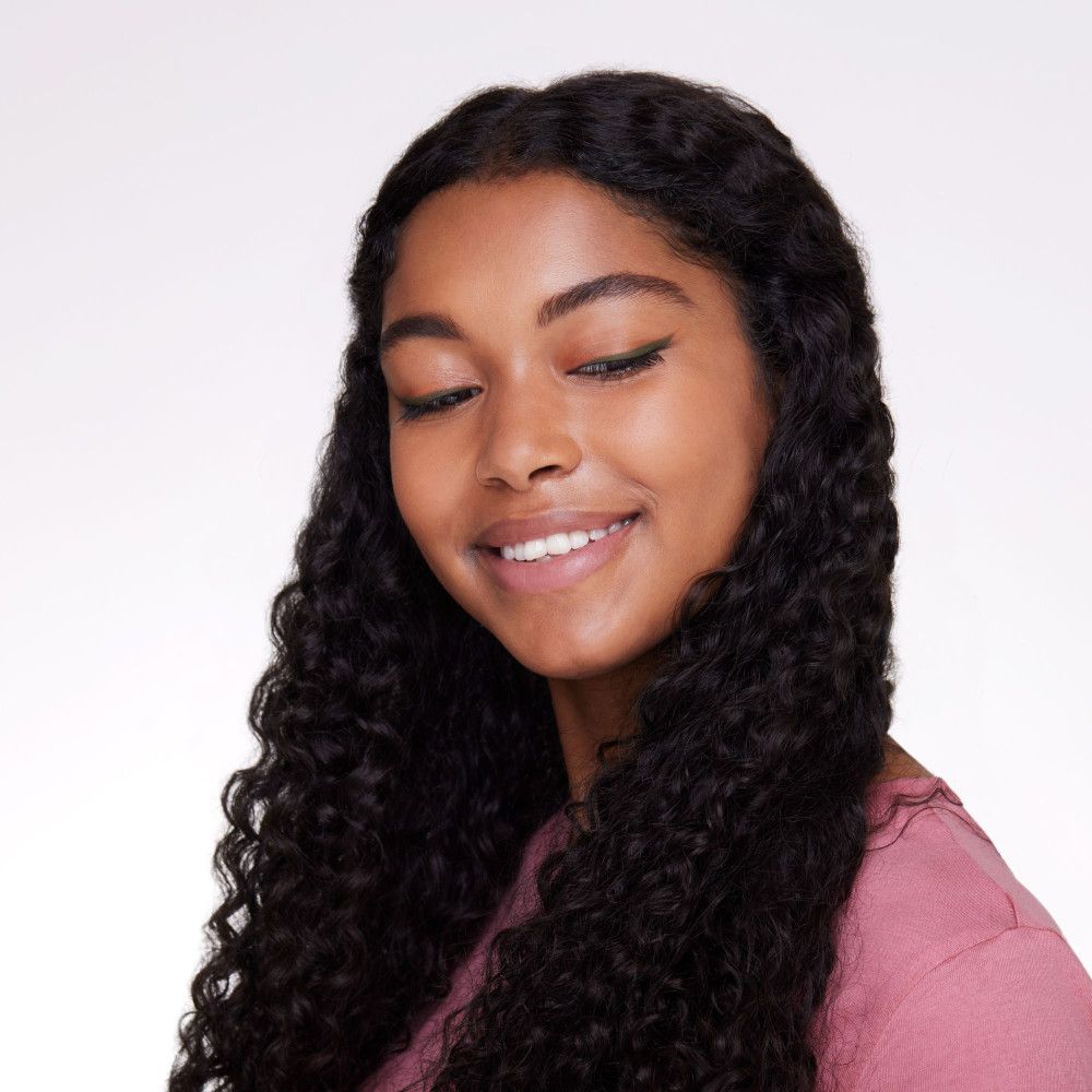 Porträt einer Frau mit langen, lockigen, schwarzen Haaren. Sie trägt einen Lidstrich.