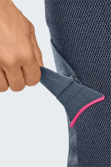 Nahaufnahme der Knieorthese. Dunkelgraues, gestricktes Material. Pinkfarbene Details. Hand berührt das Produkt.