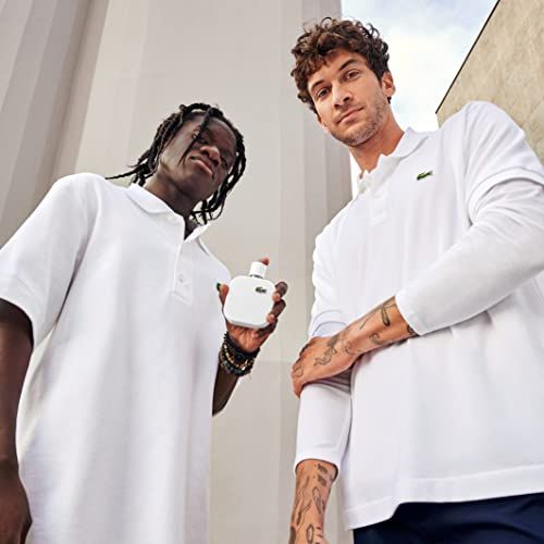 Zwei Männer in weißen Poloshirts. Einer hält ein weißes Parfüm. Hintergrund: Gebäude.