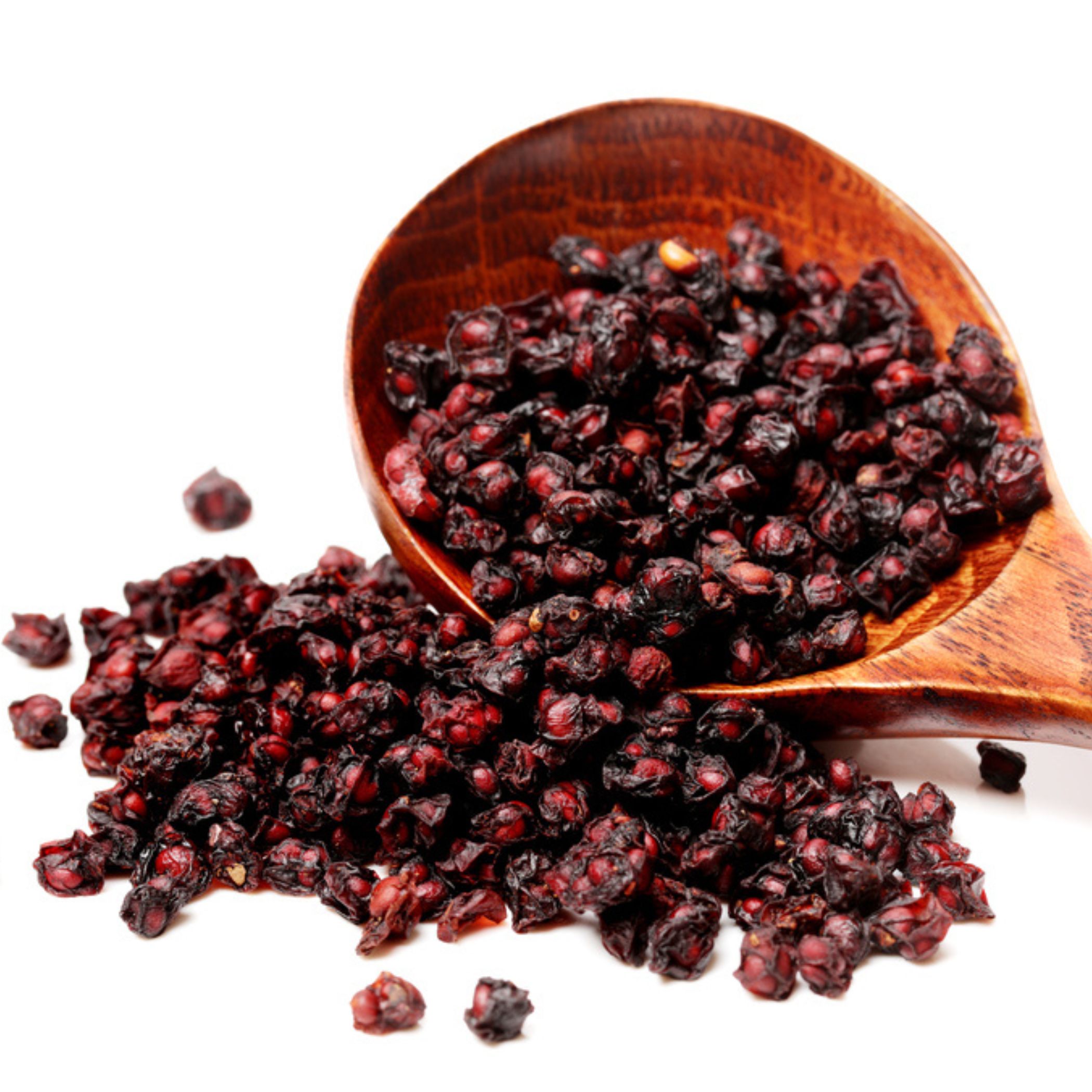 Holzlöffel mit getrockneten, roten Schisandra-Beeren. Beeren auf weißem Hintergrund verstreut.