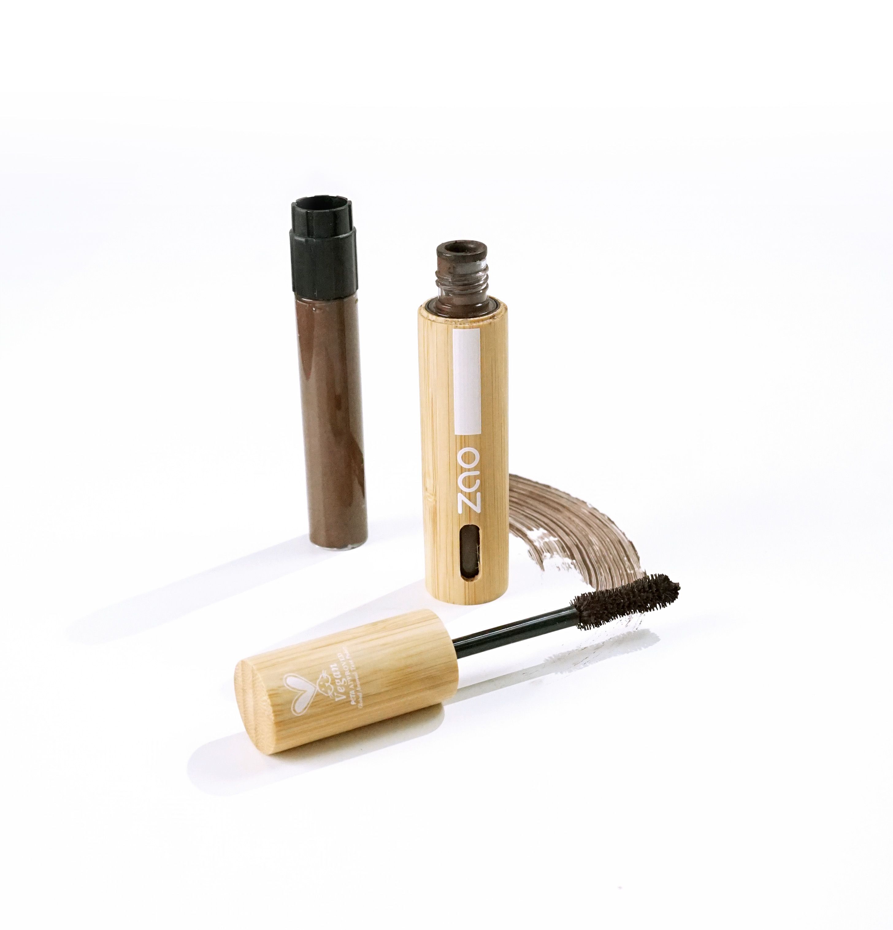 Mascara-Behälter aus Bambus mit Bürste und Deckel. Braune Mascara-Spur. Vegan-Siegel auf dem Deckel.