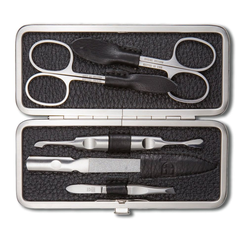 Maniküre-Set in schwarzem Etui. Enthält Schere, Nagelknipser, Feile, Hufstäbchen und Pinzette. Metall und Leder.