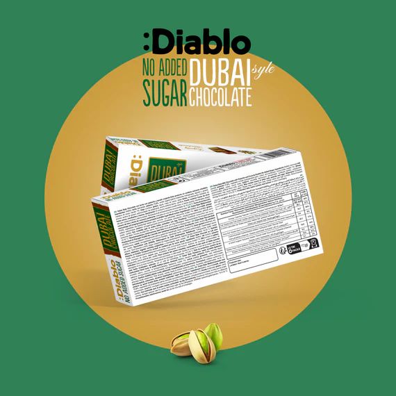 Verpackung von Diablo Dubai Schokolade ohne Zuckerzusatz. Rückseite mit Text und Nährwertangaben. Pistazien liegen daneben.