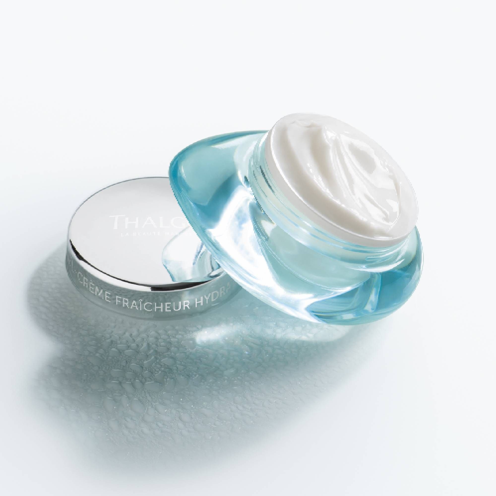Geöffneter türkisfarbener Tiegel mit silbernem Deckel. Aufschrift: THALGO, CRÈME FRAÎCHEUR HYDRATANT. Produktansicht.
