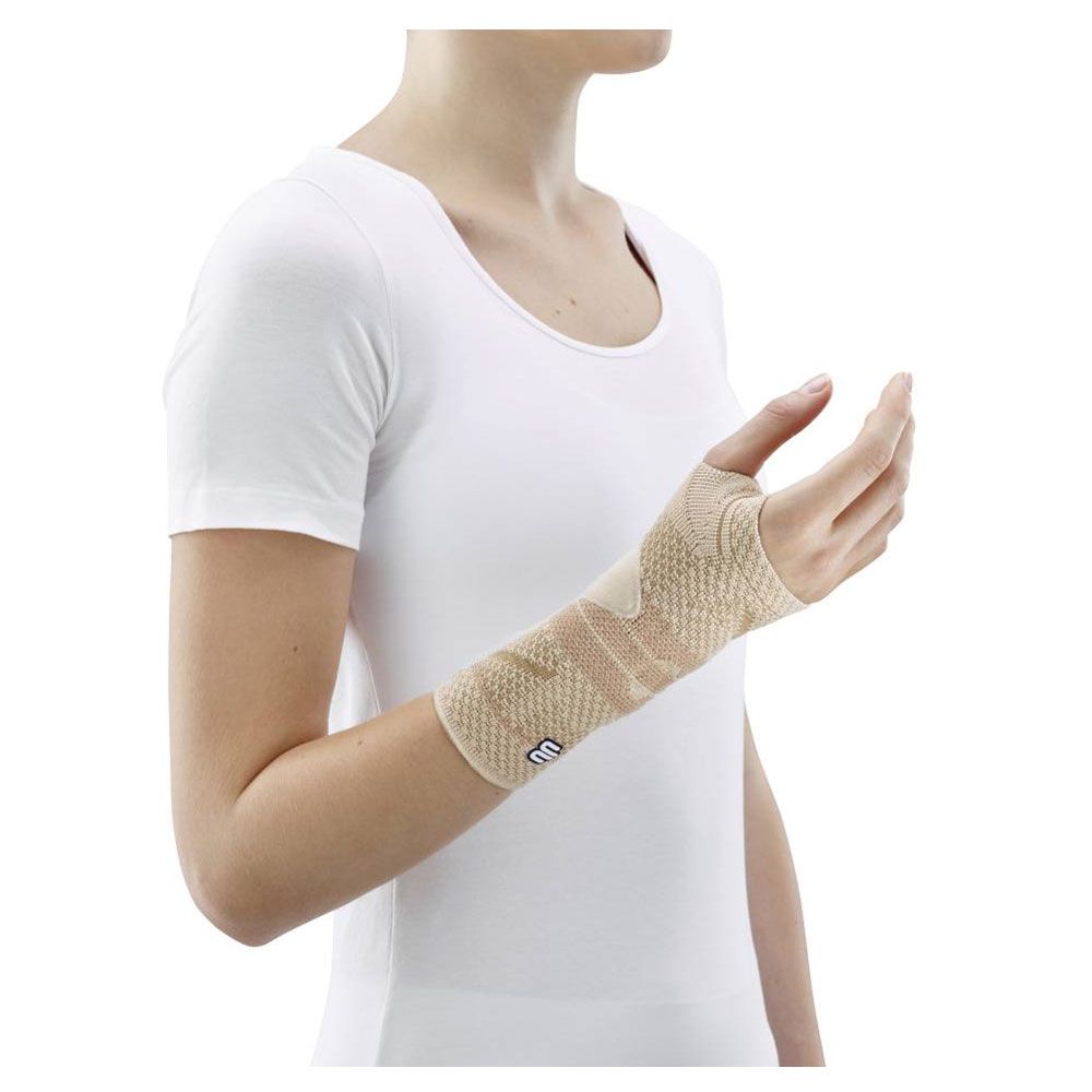 Handgelenkbandage, beige, am Handgelenk einer Person. Offenes Design für die Finger. Marke sichtbar.