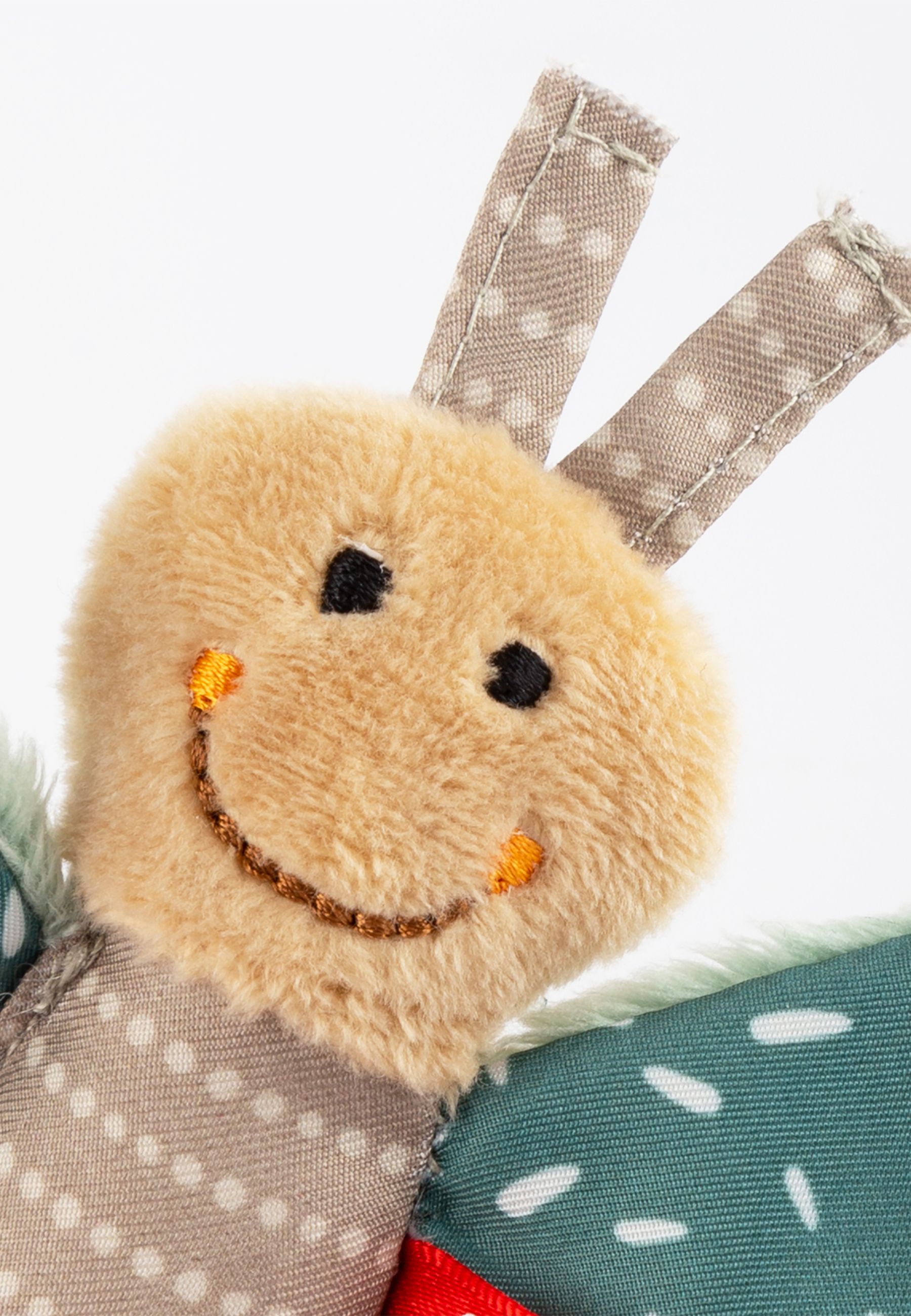 Nahaufnahme des Schmetterlingskopfes. Beige, mit gesticktem Lächeln und Augen. Ohne Etikett.