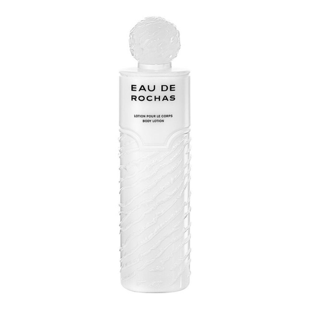 Weiße Flasche mit geriffelter Oberfläche. Oben steht "EAU DE ROCHAS". Darunter "LAIT PARFUMÉ POUR LE CORPS".