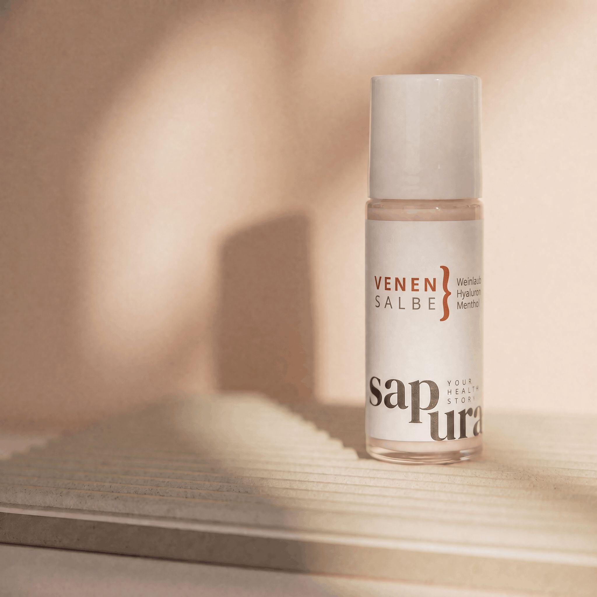 Venensalbe Roll-On auf einer hellen Oberfläche mit Schatten.