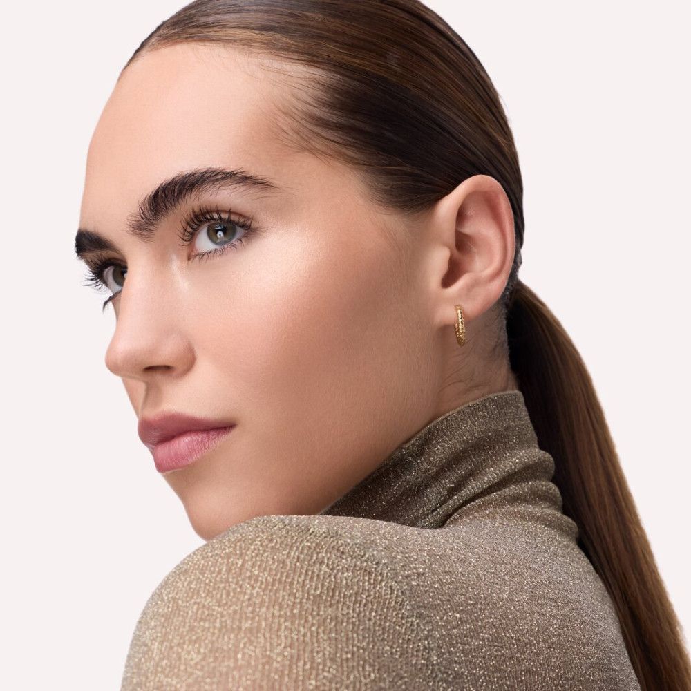 Porträt einer Frau mit Make-up. Highlighter auf dem Gesicht. Goldener Rollkragenpullover.