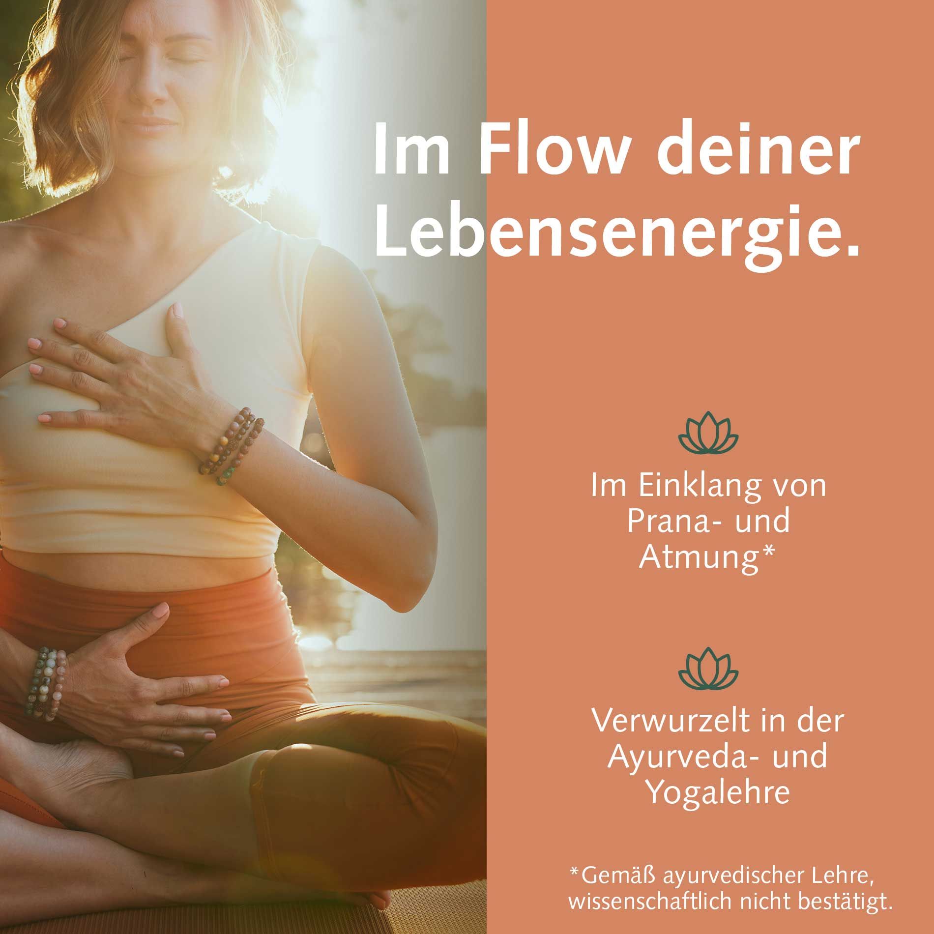 Frau in Meditationshaltung mit geschlossenen Augen und Hand auf der Brust.