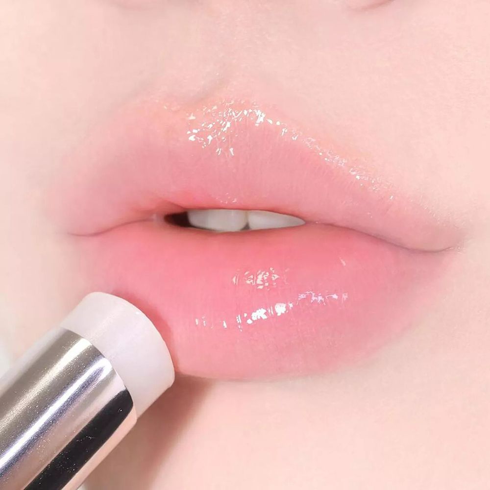 Nahaufnahme von Lippen mit glänzendem Lippenbalsam. Der Lippenbalsam wird aufgetragen.