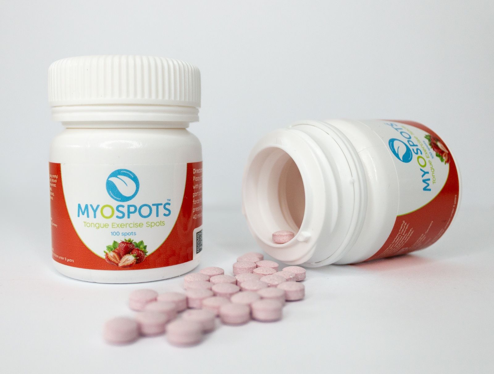 Zwei Flaschen mit Tabletten. Produktname und Logo auf der Flasche. Rosa Tabletten daneben.