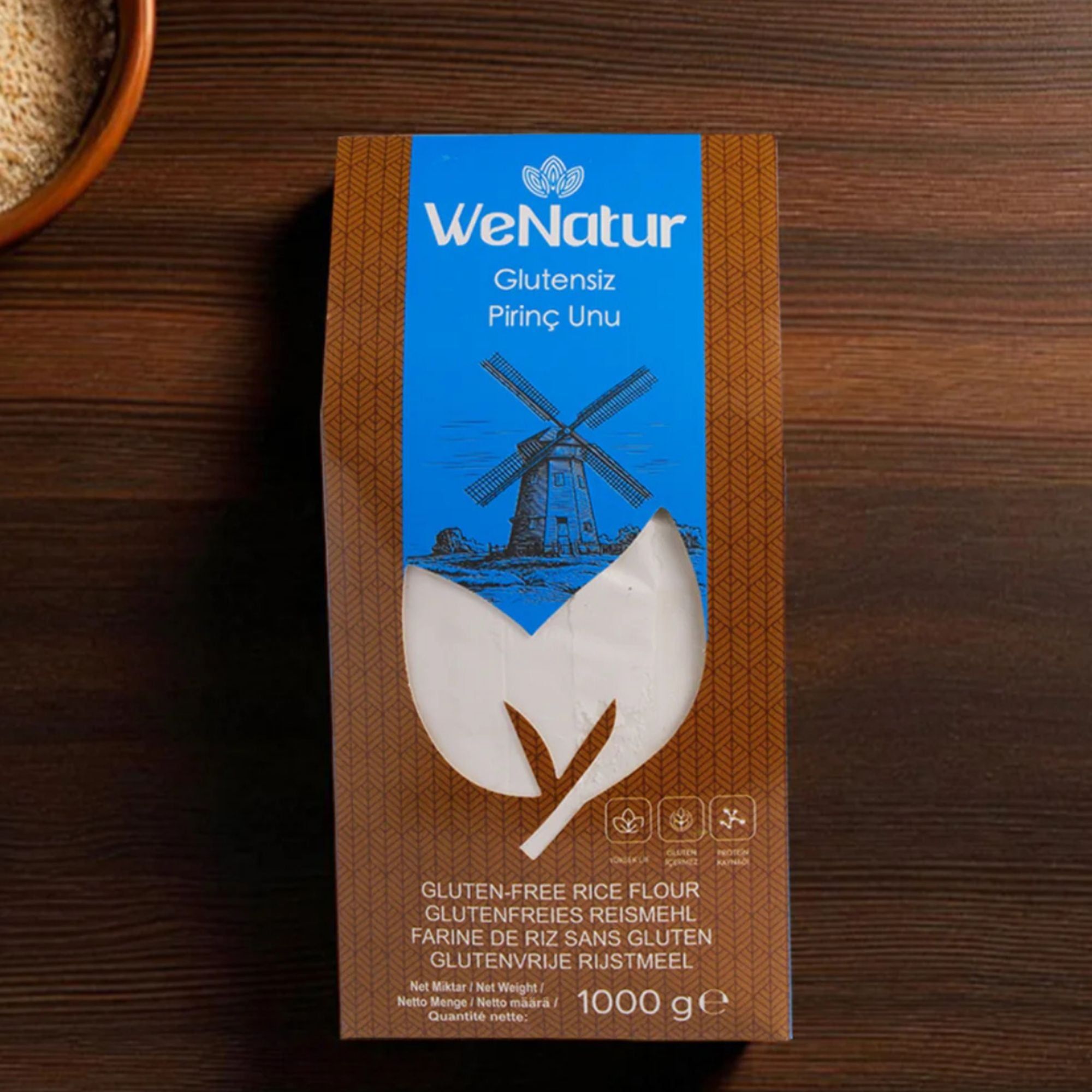WeNatur glutenfreies Reismehl, 1000g Packung auf einem Holztisch.