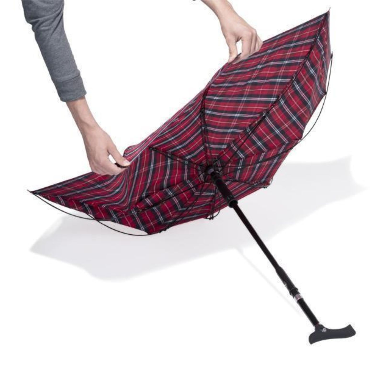 Regenschirm mit rot-schwarz kariertem Muster, wird von Händen geöffnet.