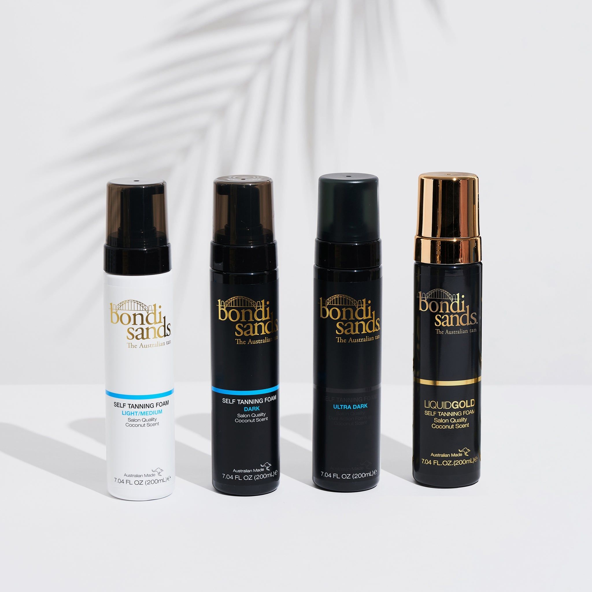 Vier Flaschen Selbstbräunungsschaum. Aufschriften: Bondi Sands, Light Medium, Dark, Ultra Dark, Liquid Gold. Schwarze und weiße Flaschen.