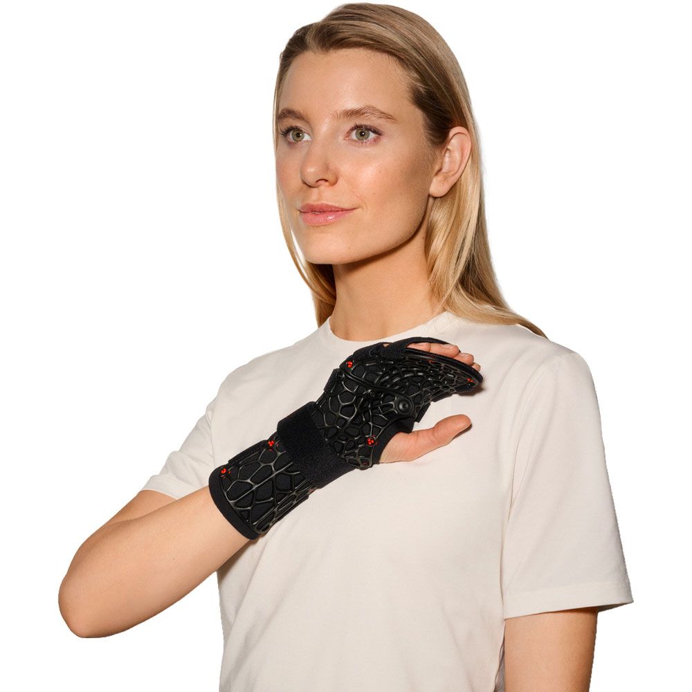 Frau trägt eine schwarze Handgelenkorthese mit offenem Gittermuster am linken Handgelenk.