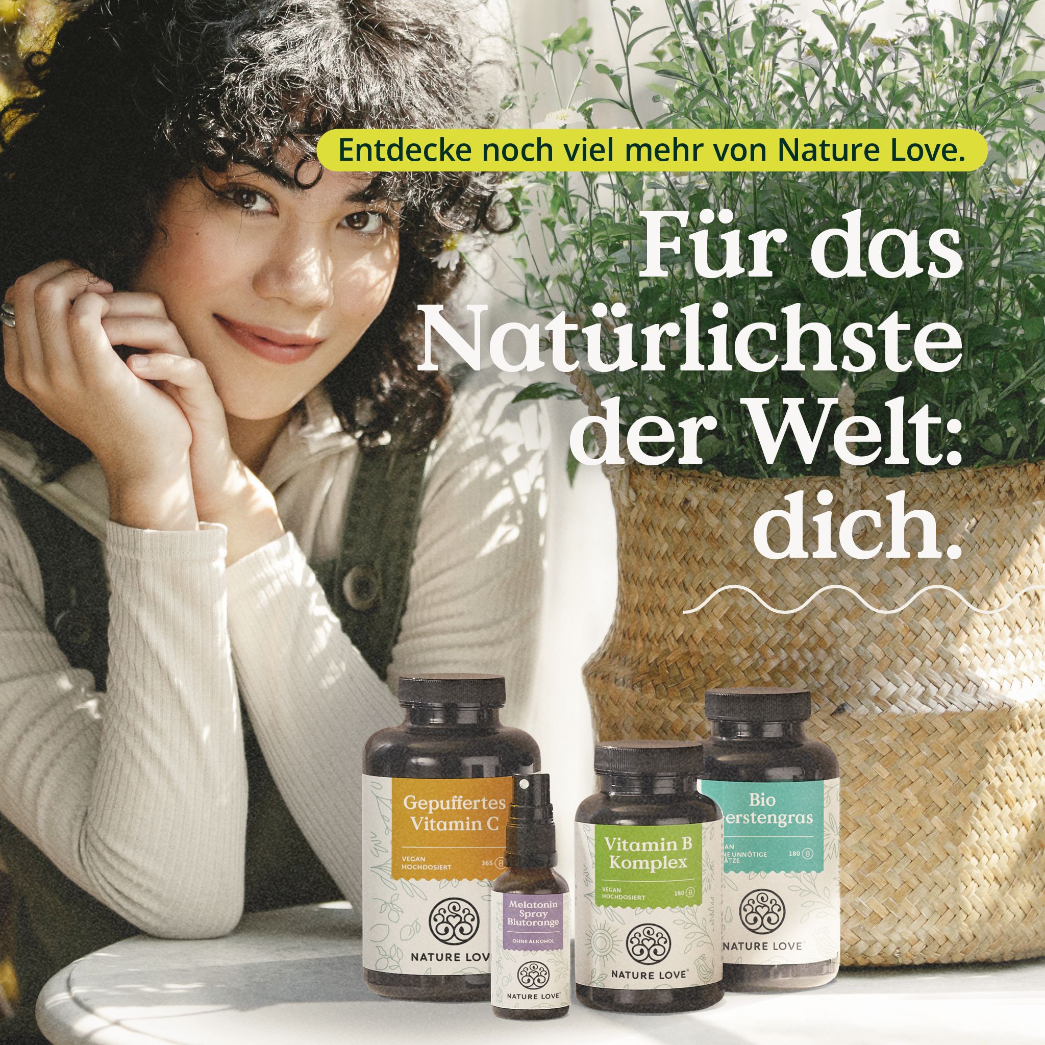 Frau mit Produkten von NATURE LOVE®. Flaschen: Vitamin C, Vitamin B Komplex, Bio erstengras. Korb mit Pflanze.