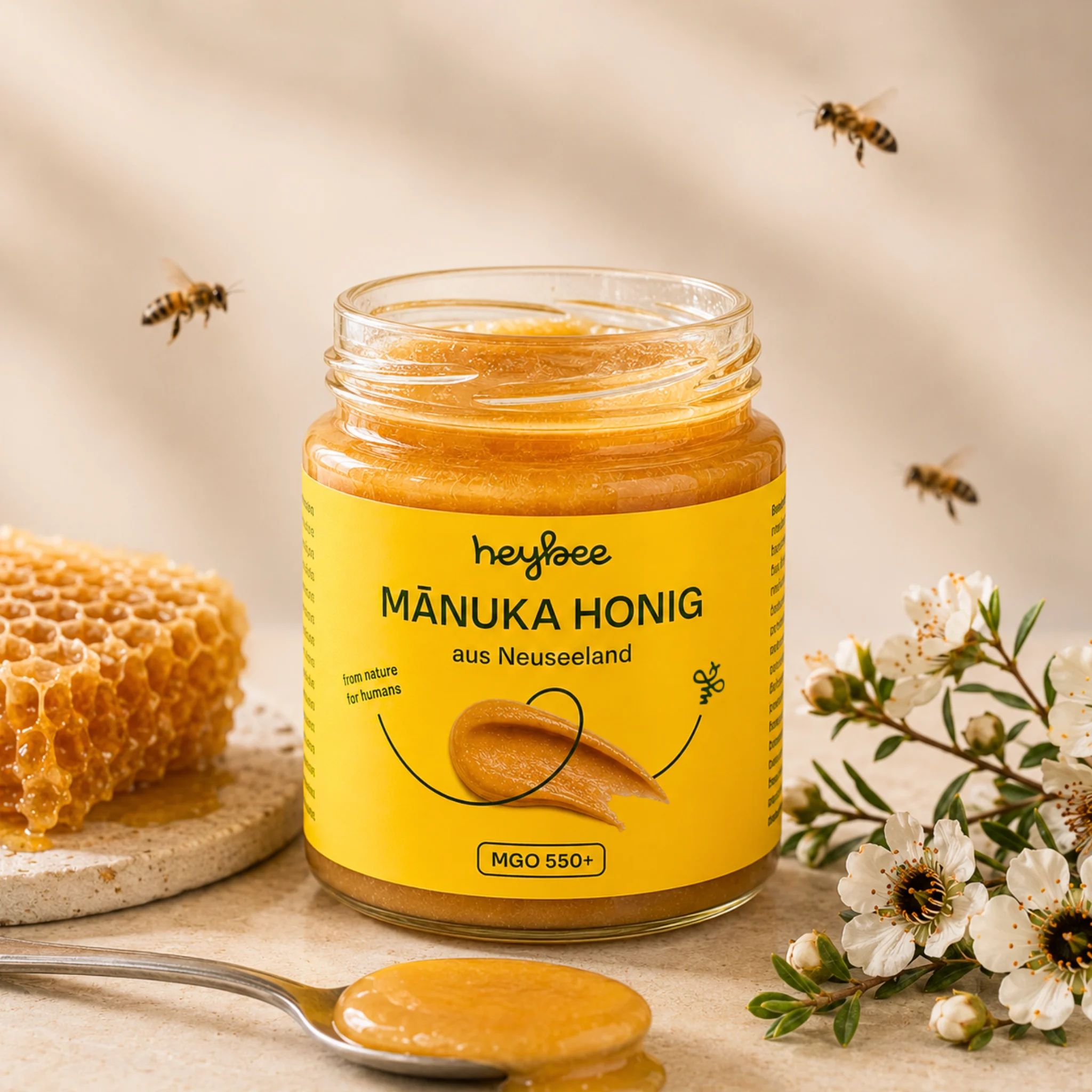 Glas Manuka Honig MGO 550+. Honigwabe und Blumen neben dem Glas.