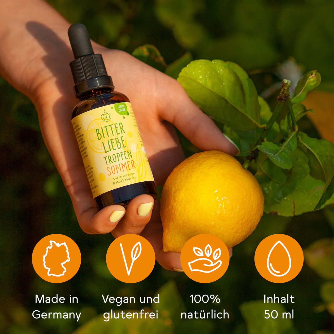 Hand hält braune Flasche mit Pipette und Zitrone. Auf dem Etikett steht "BitterLiebe Tropfen Sommer".