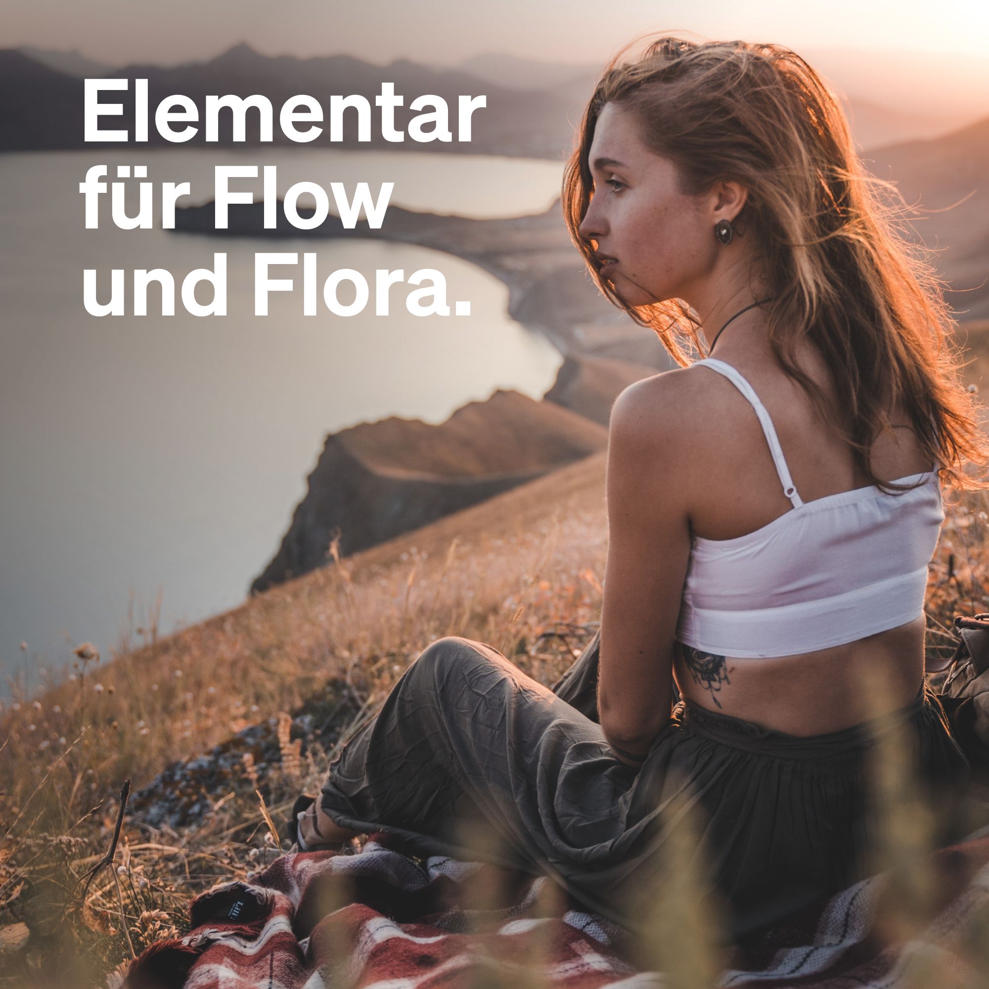 Eine Frau sitzt auf einem Hügel und blickt auf einen See. Text: Elementar für Flow und Flora.