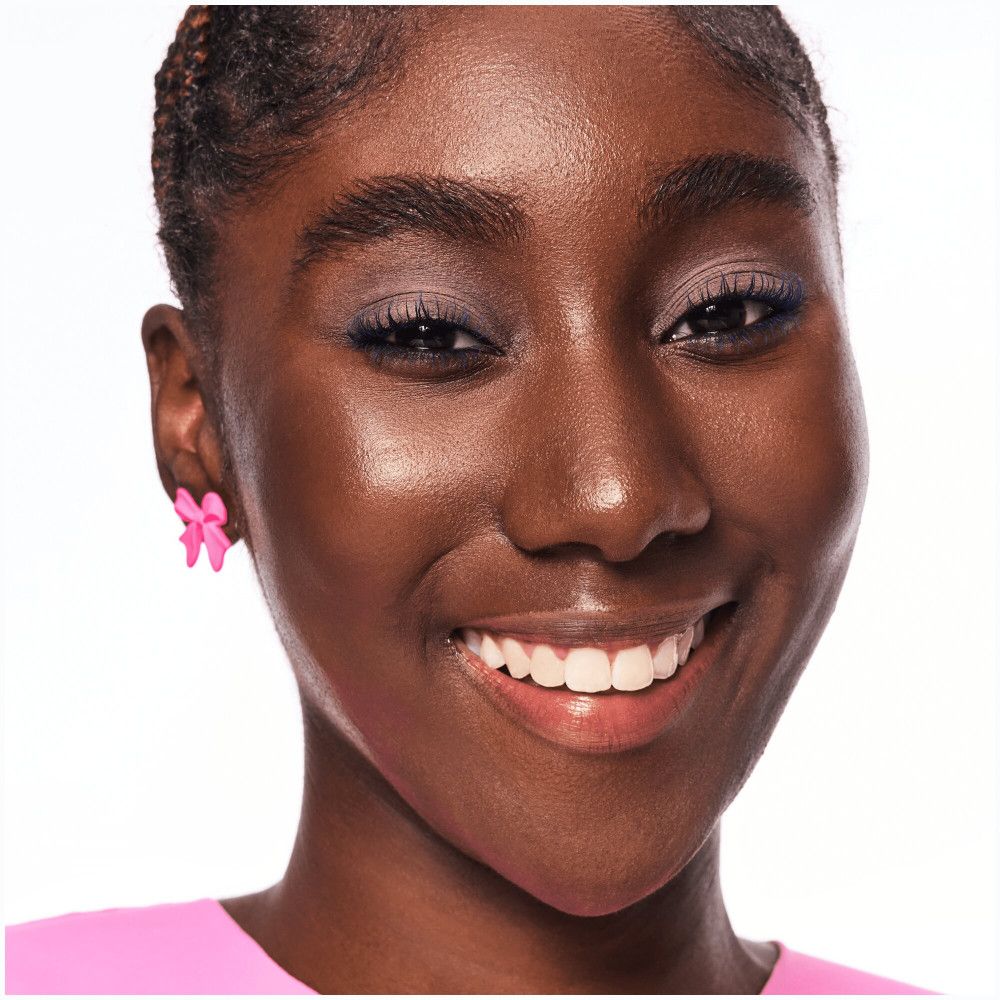 Porträt einer Frau mit Lippenstift. Sie lächelt. Rosa Ohrringe.