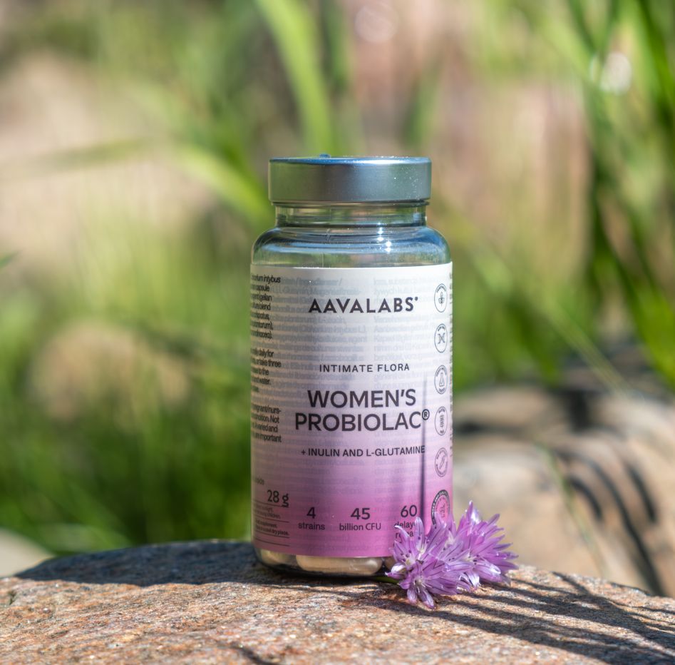 Flasche Aavalabs Women's Probiolac auf einem Stein mit einer Blume.
