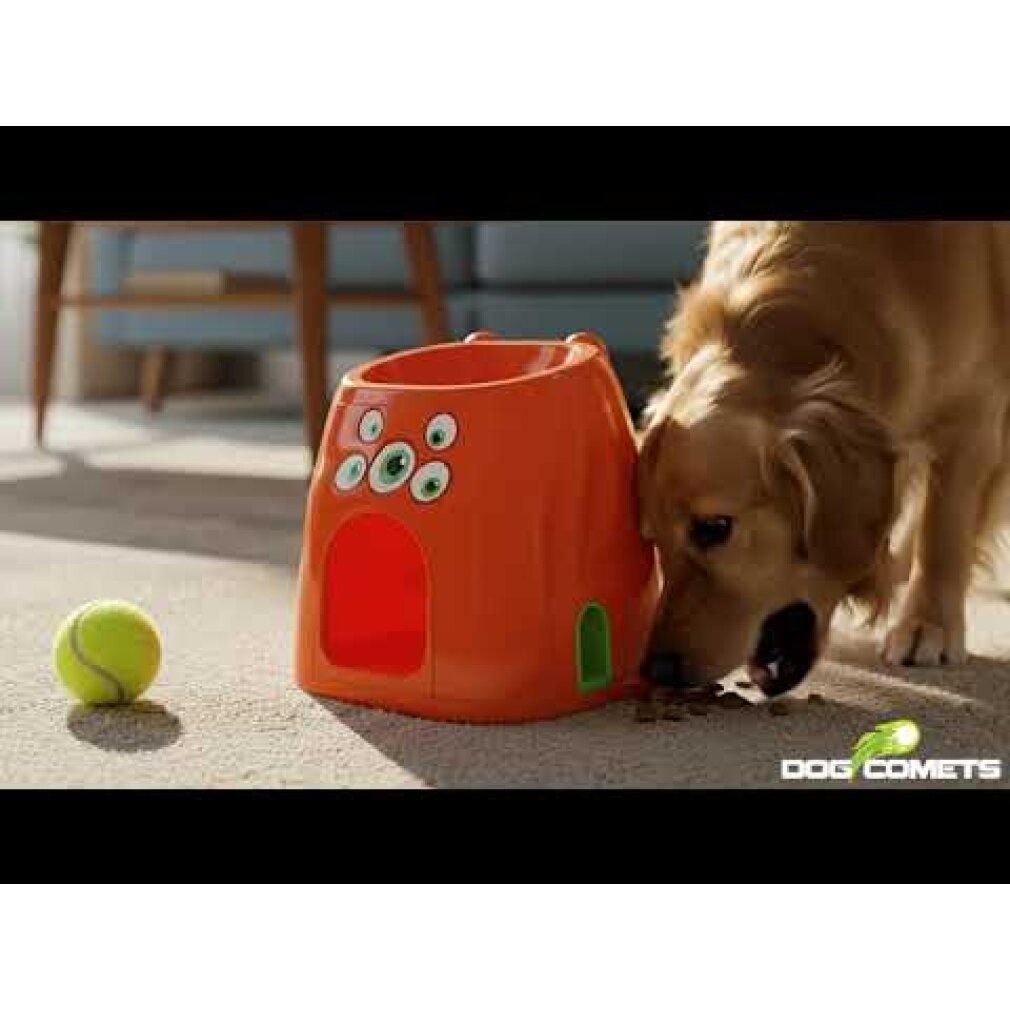 Orangefarbenes Gerät mit drei Augen. Hund frisst Futter. Tennisball daneben. Logo: Dog Comets.