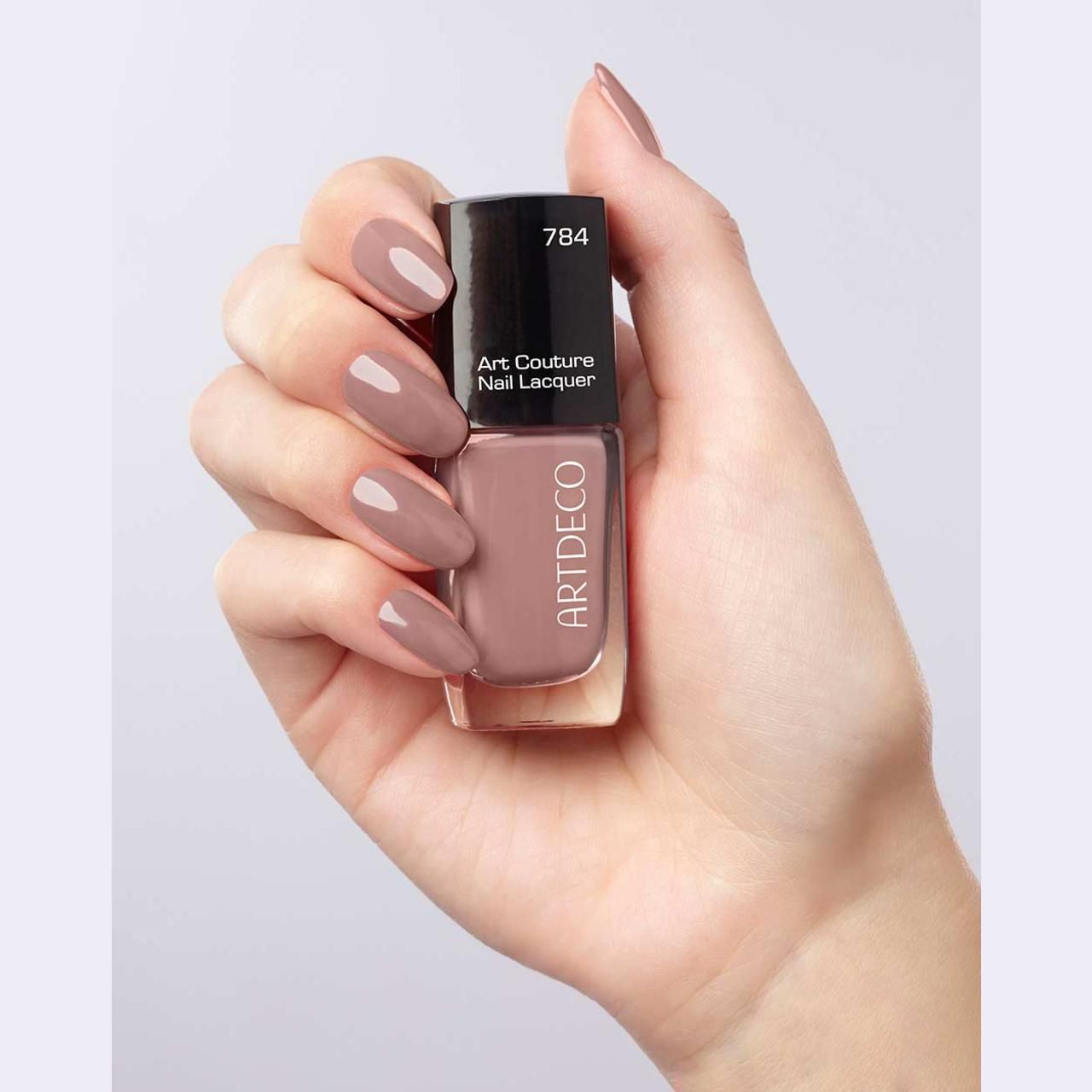 Hand hält Nagellackflasche und lackierte Nägel. Aufschrift: Art Couture Nail Lacquer und ARTDECO.