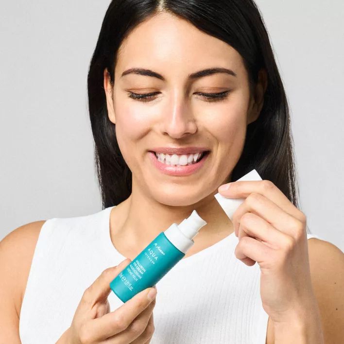 Frau öffnet eine türkisfarbene Flasche. Aufschrift: M. Asam AQUA INTENSE Hyaluron Eye Cream.