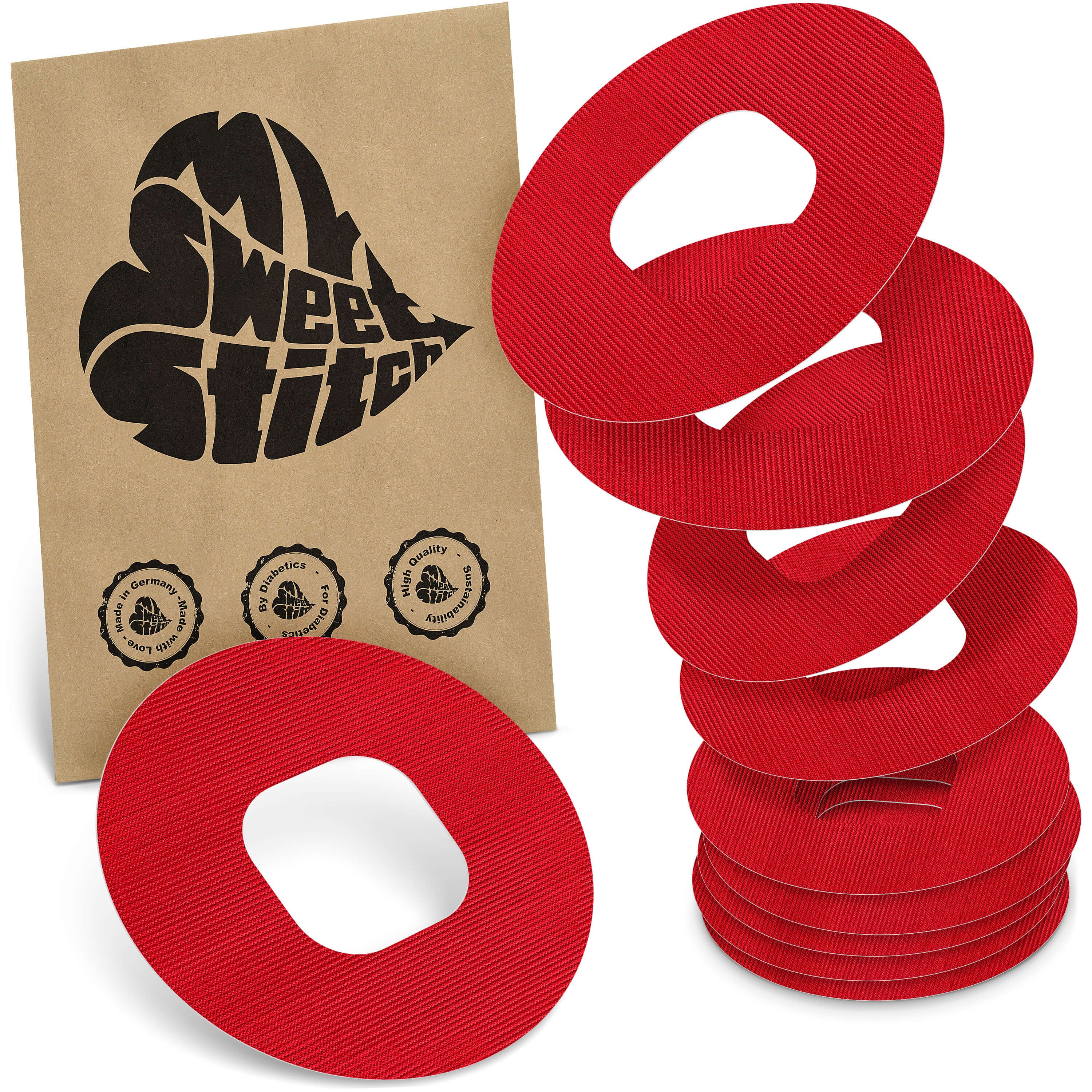 Rote, ovale Pflaster mit Aussparung, gestapelt und einzeln. Braune Packung mit Herz-Logo.