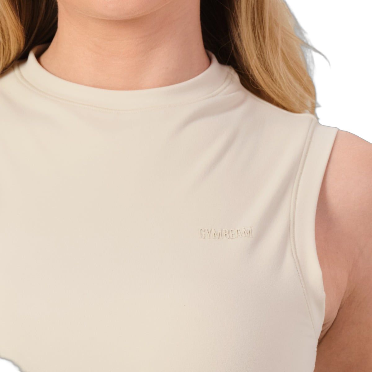 Nahaufnahme des Ausschnitts eines ärmellosen, cremefarbenen Tops mit dezentem Logo.