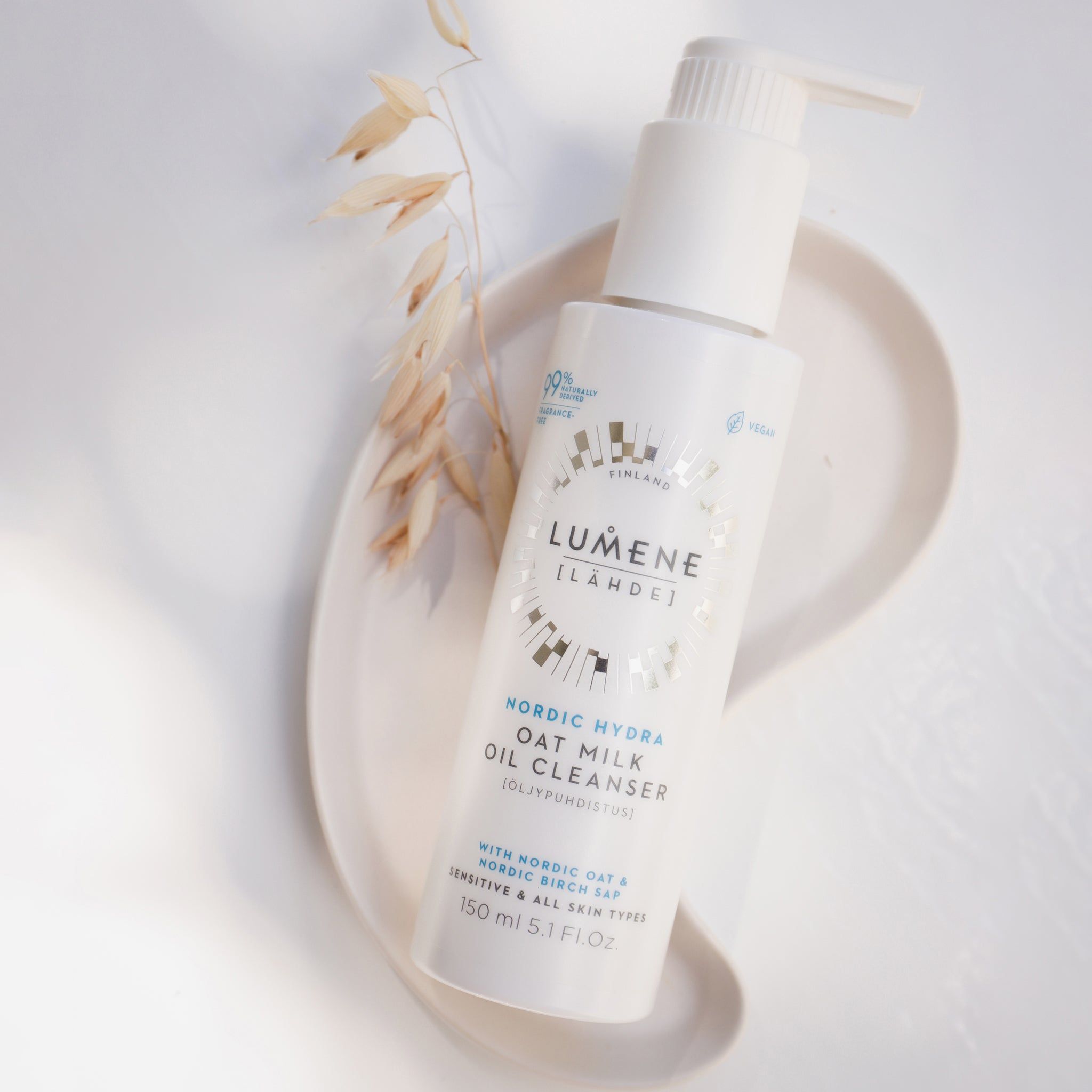 Weiße Flasche mit Pumpe auf einem Tablett. Aufschrift: Lumene Nordic Hydra Oat Milk Oil Cleanser. Mit Hafermilch. 99% natürlich.