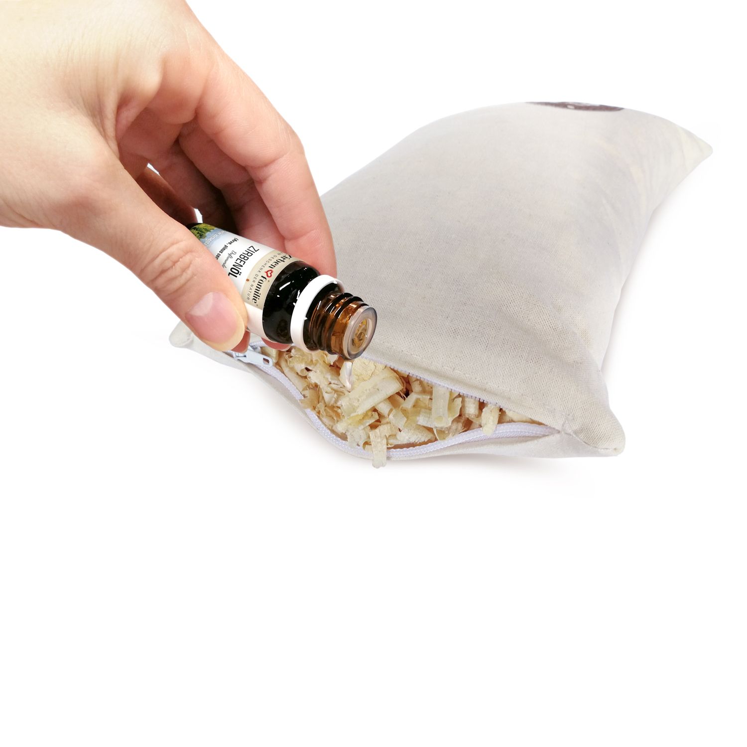 Hand beträufelt Kissenfüllung mit Öl. Ölflasche sichtbar.