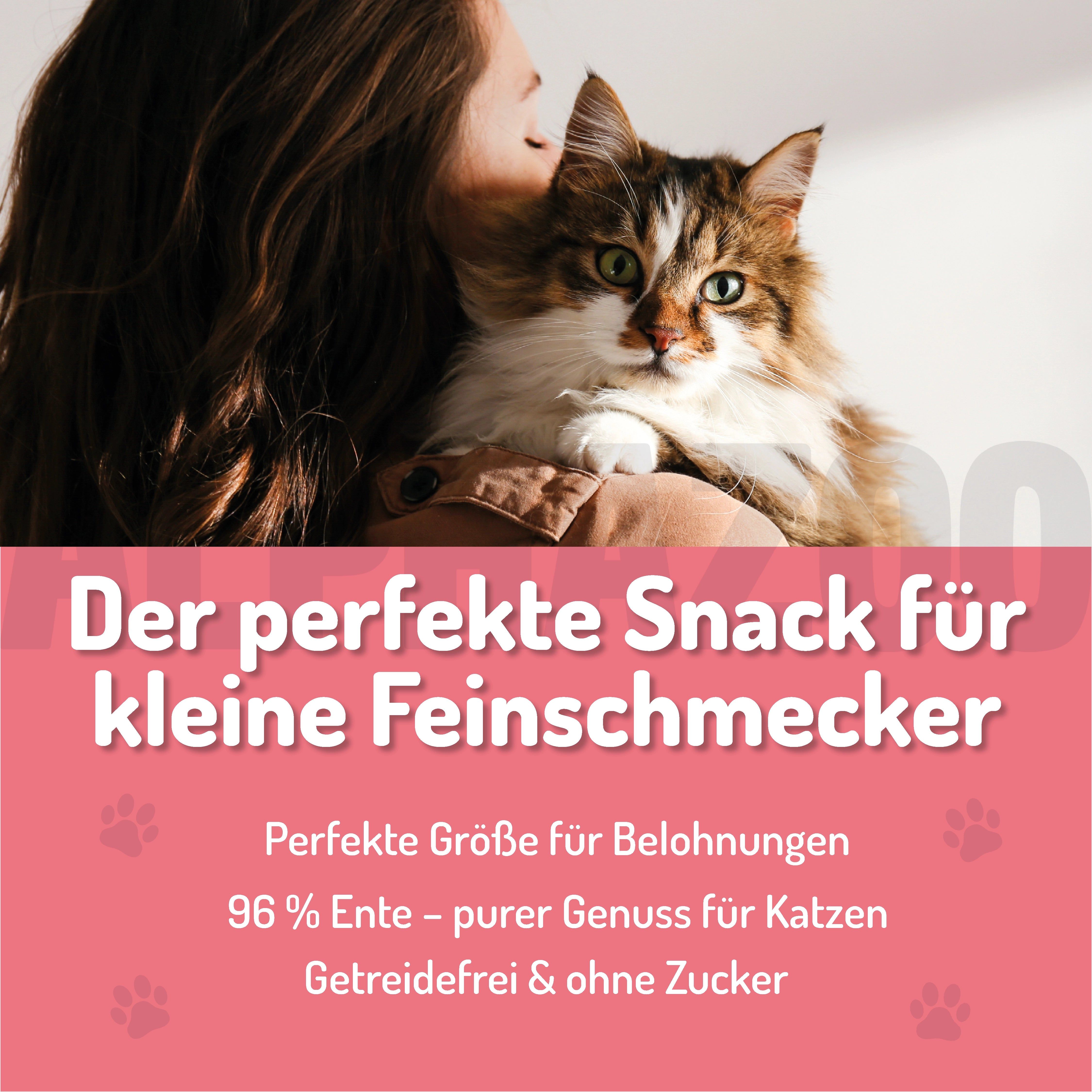 Katze auf Schulter einer Person. Rosa Hintergrund mit Text: Der perfekte Snack für kleine Feinschmecker. 96% Ente, getreidefrei.