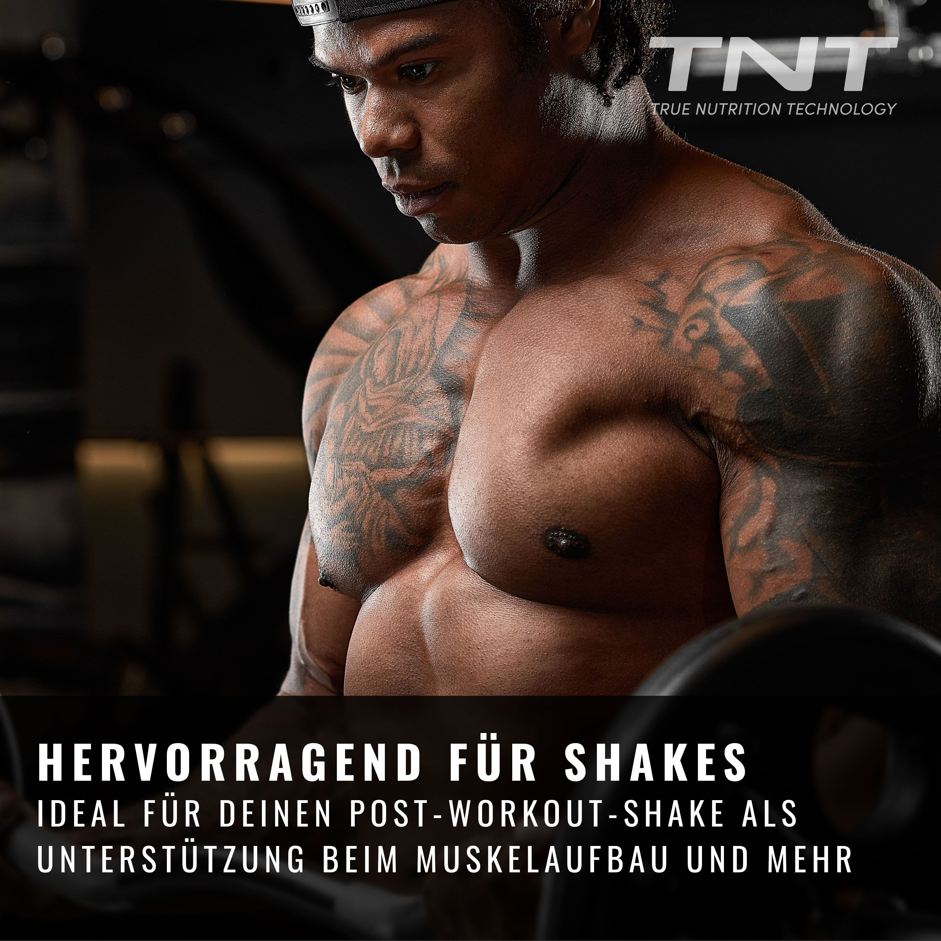 Muskulöser Mann im Fitnessstudio. Im Hintergrund ein pinkfarbener Behälter mit MALTO DEXTRIN DE12 und TNT Logo.