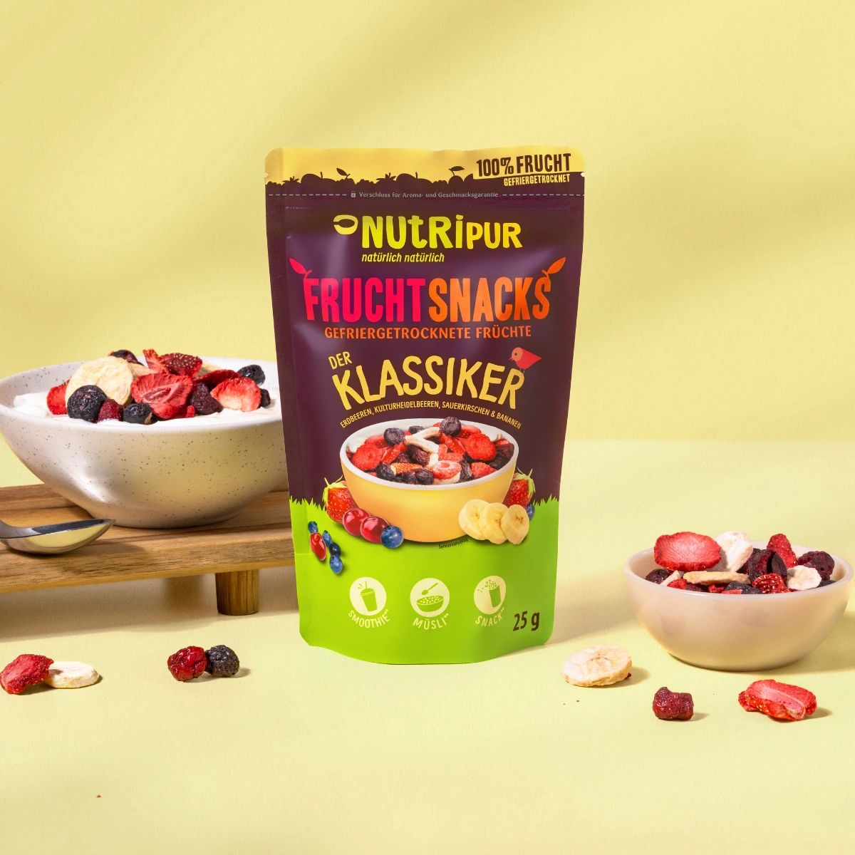 Schale mit Früchten auf Joghurt. Daneben Beutel mit gefriergetrockneten Früchten. Kleine Schale mit Früchten.