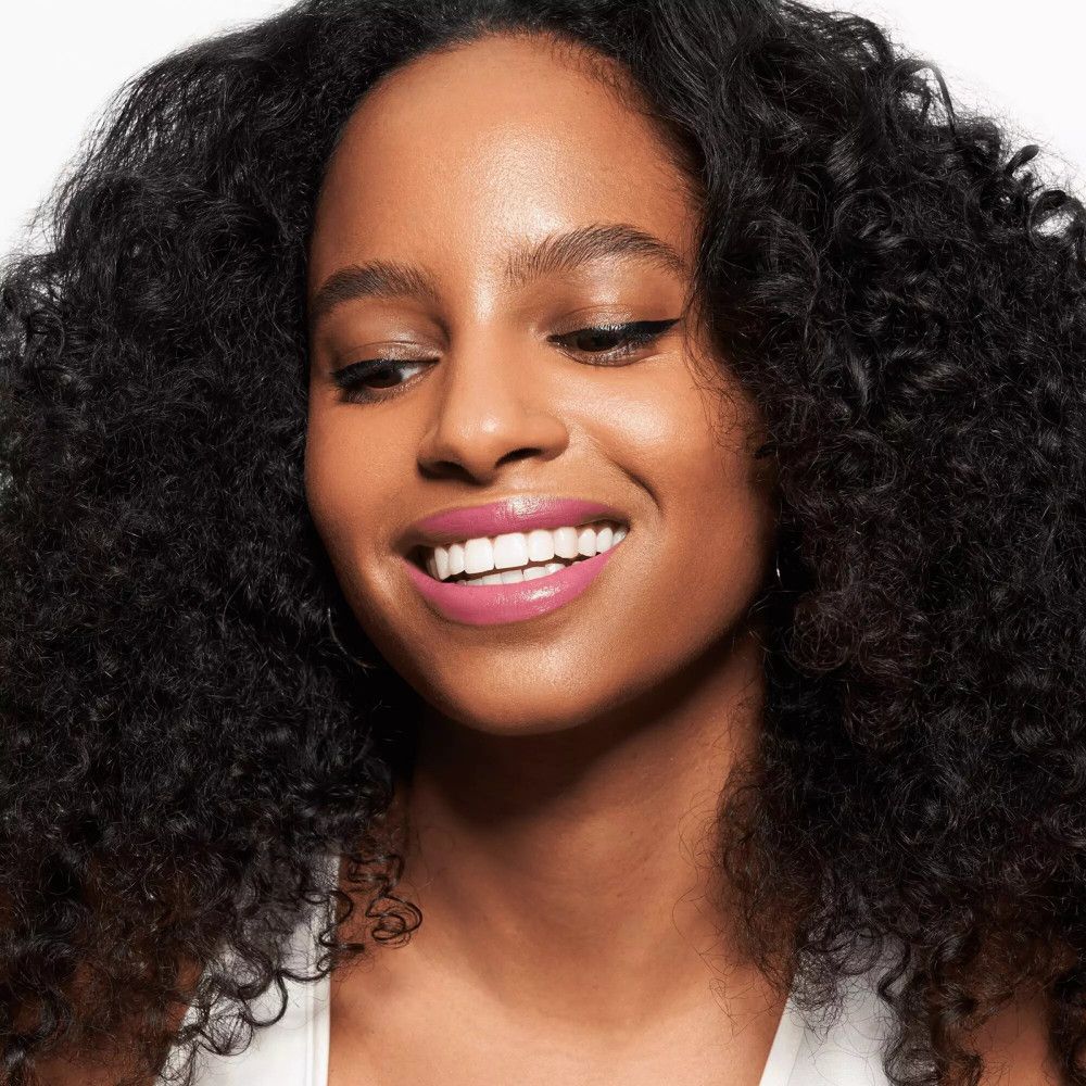 Frau mit Locken und rosa Lippenstift. Schwarzer Lidstrich.