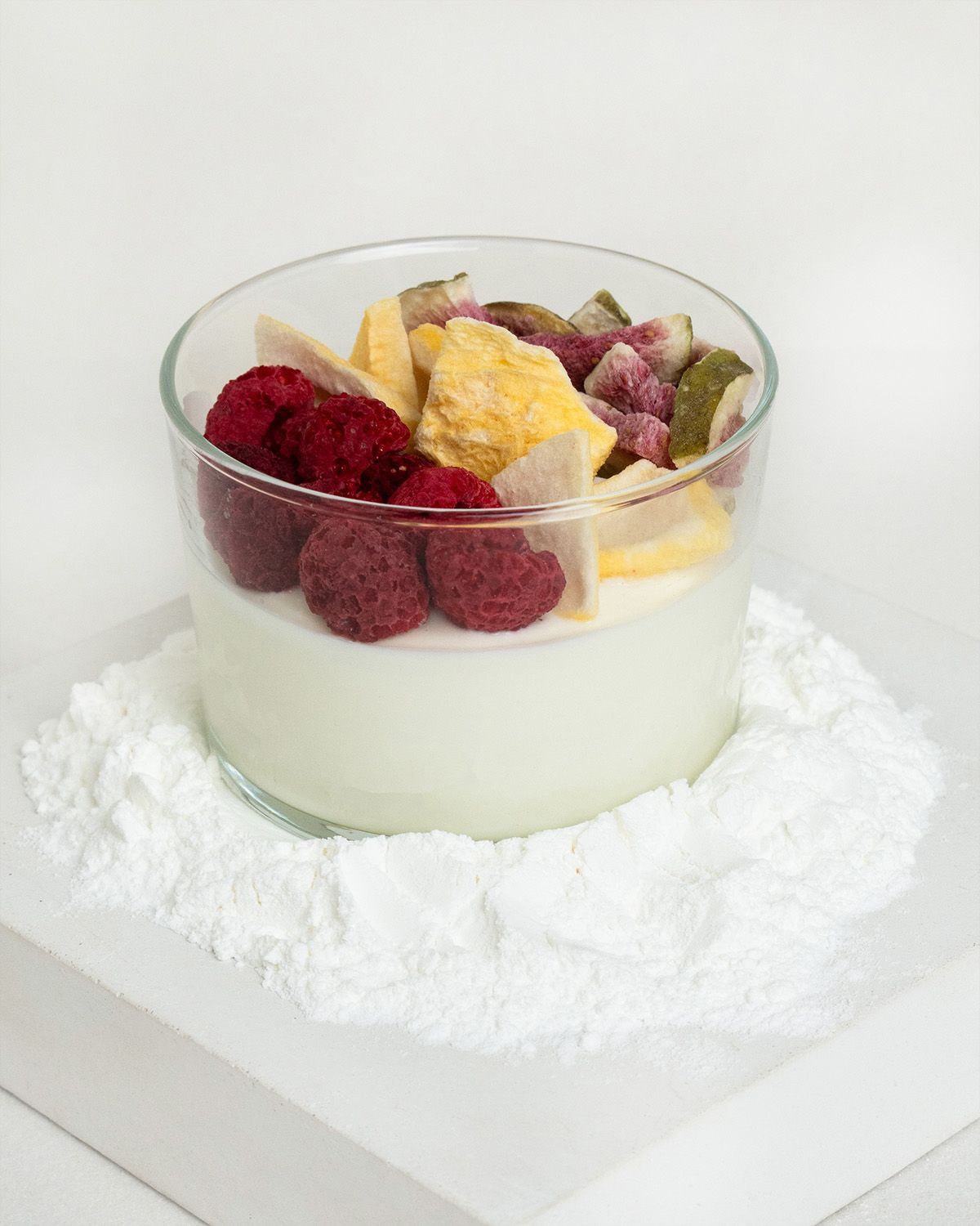 Glas mit Joghurt, Beeren und Trockenfrüchten, umgeben von Stevia-Pulver.