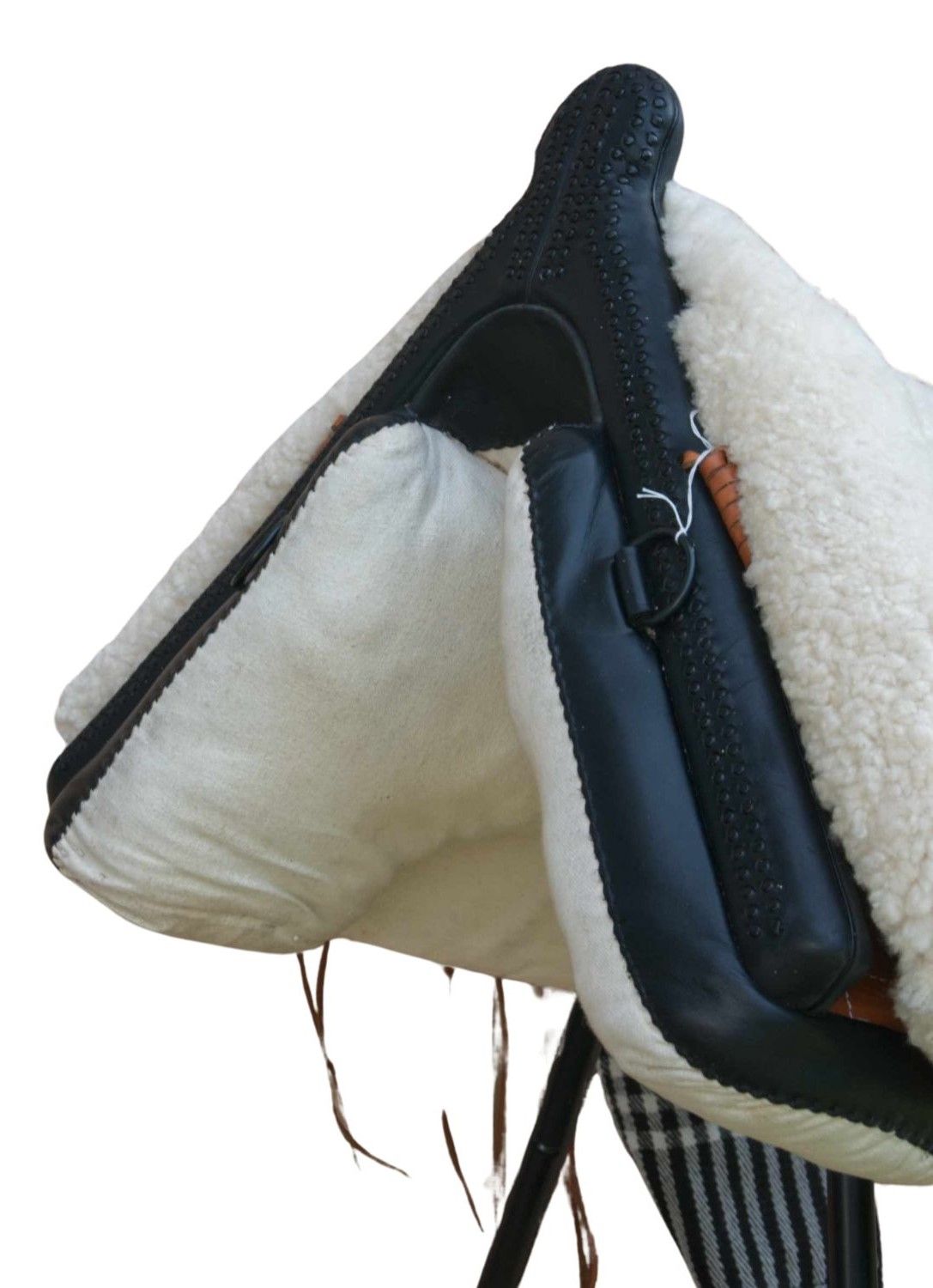 Schwarzer Sattel mit weißem Fellfutter. Lederdetails und braune Riemen. Nahaufnahme, isoliert auf weißem Hintergrund.