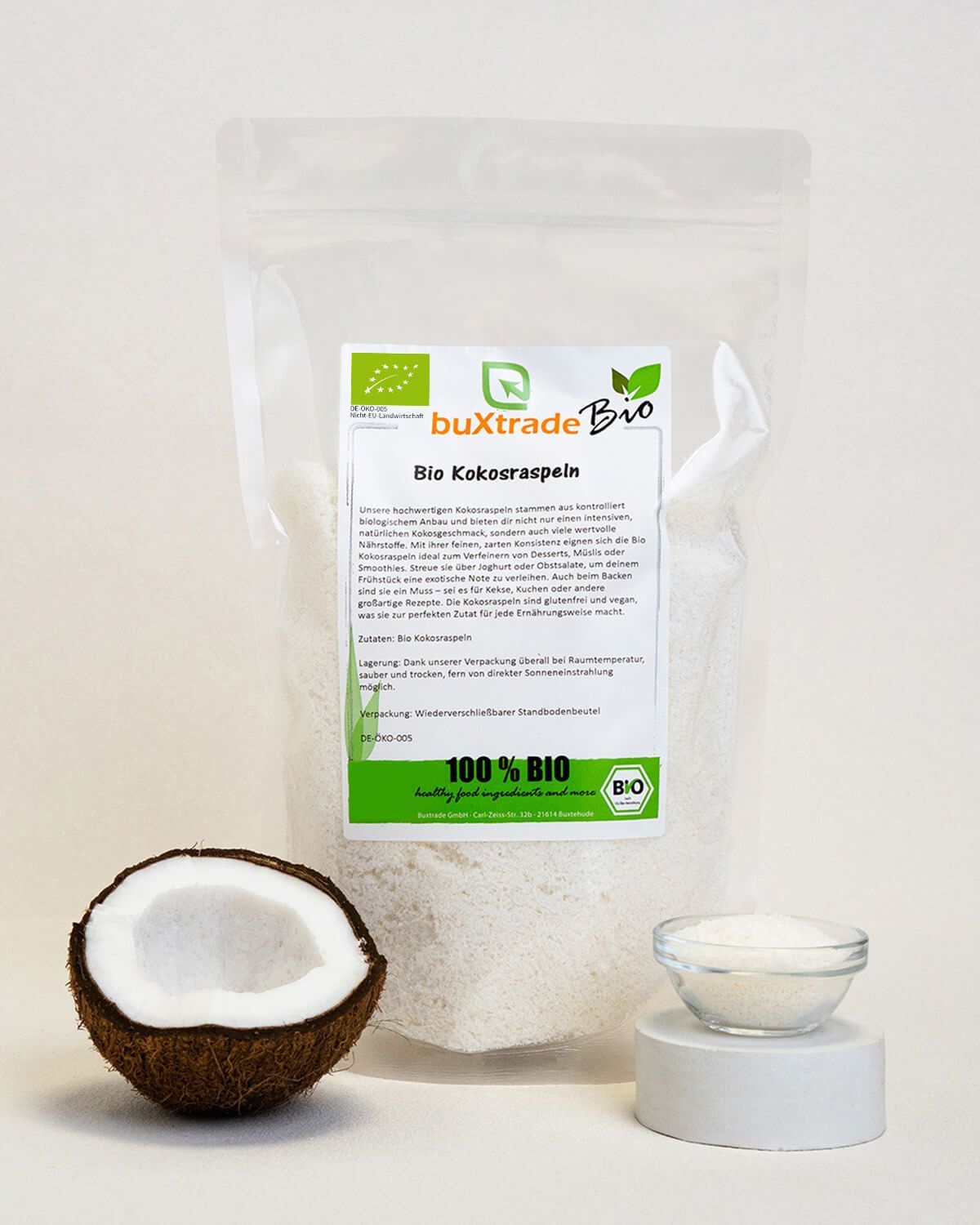 Verpackung mit Kokosraspeln, halbe Kokosnuss und Schale mit Raspeln.