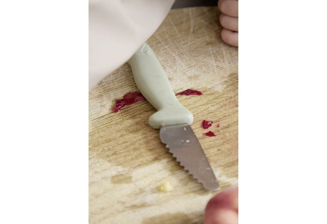 Grünes Messer auf Holzbrett. Zähne an der Klinge. Wal-Design am Griff. Marke FILIBABBA.