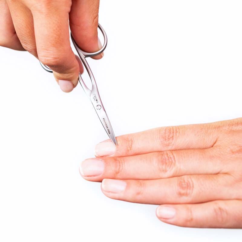 Nagelschere für Linkshänder in Anwendung. Hände schneiden einen Fingernagel. Marke REMOS, Schriftzug 'stainless-inox' sichtbar.